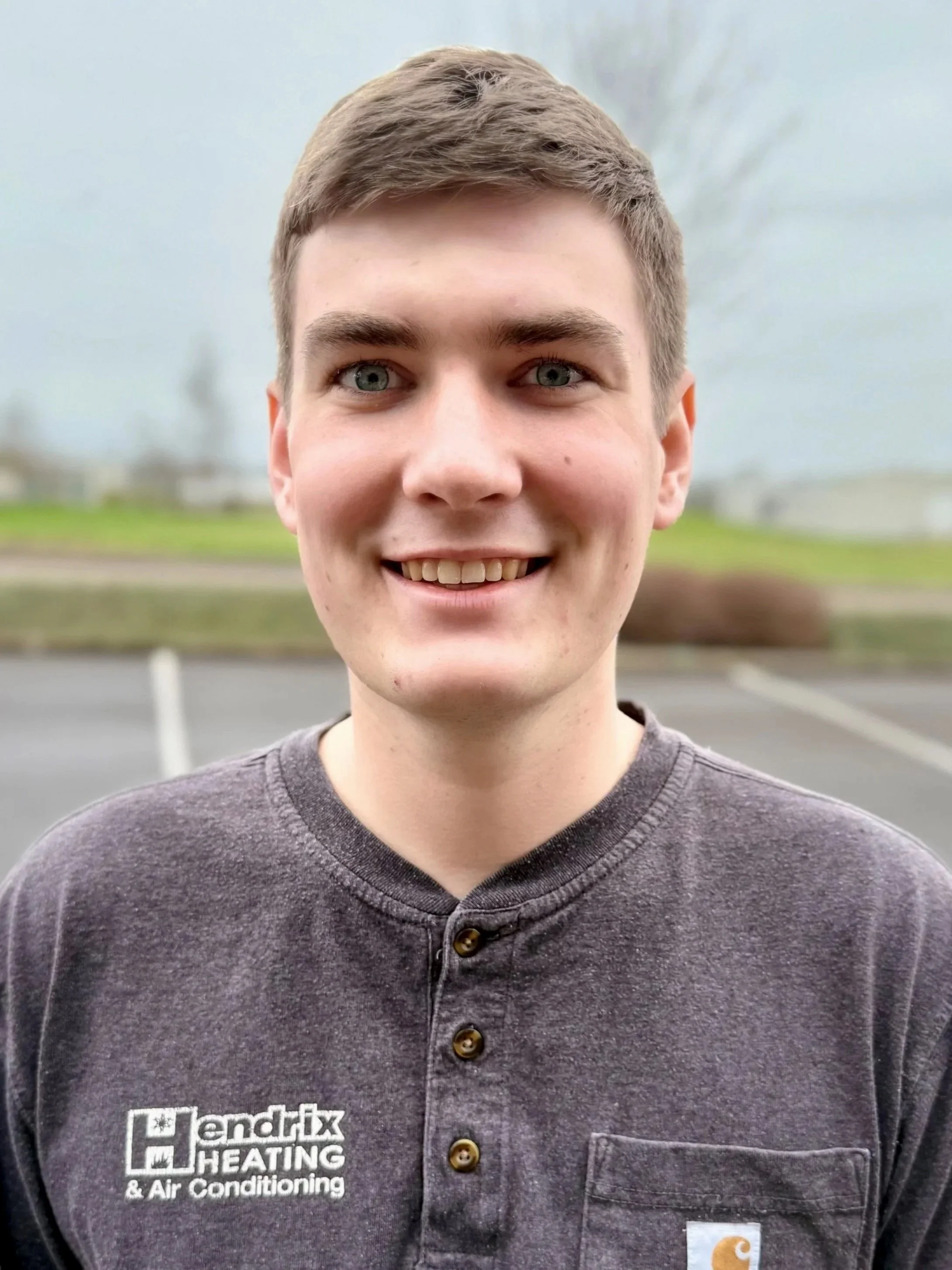 Person wearing a Hendrix Heating & Air Conditioning shirt, standing outdoors with trees in the background.