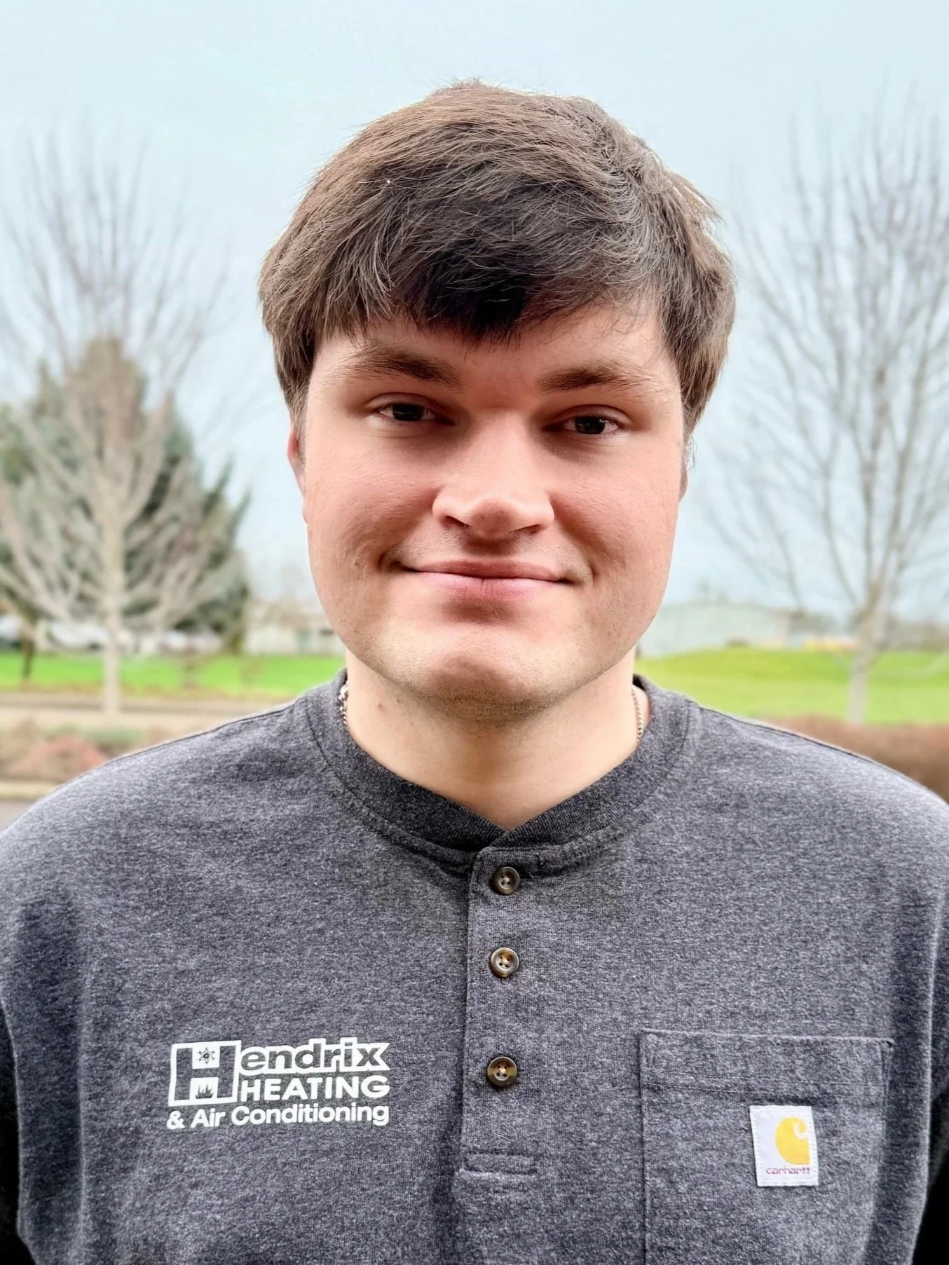 Person in a Hendrix Heating & Air Conditioning shirt standing outdoors