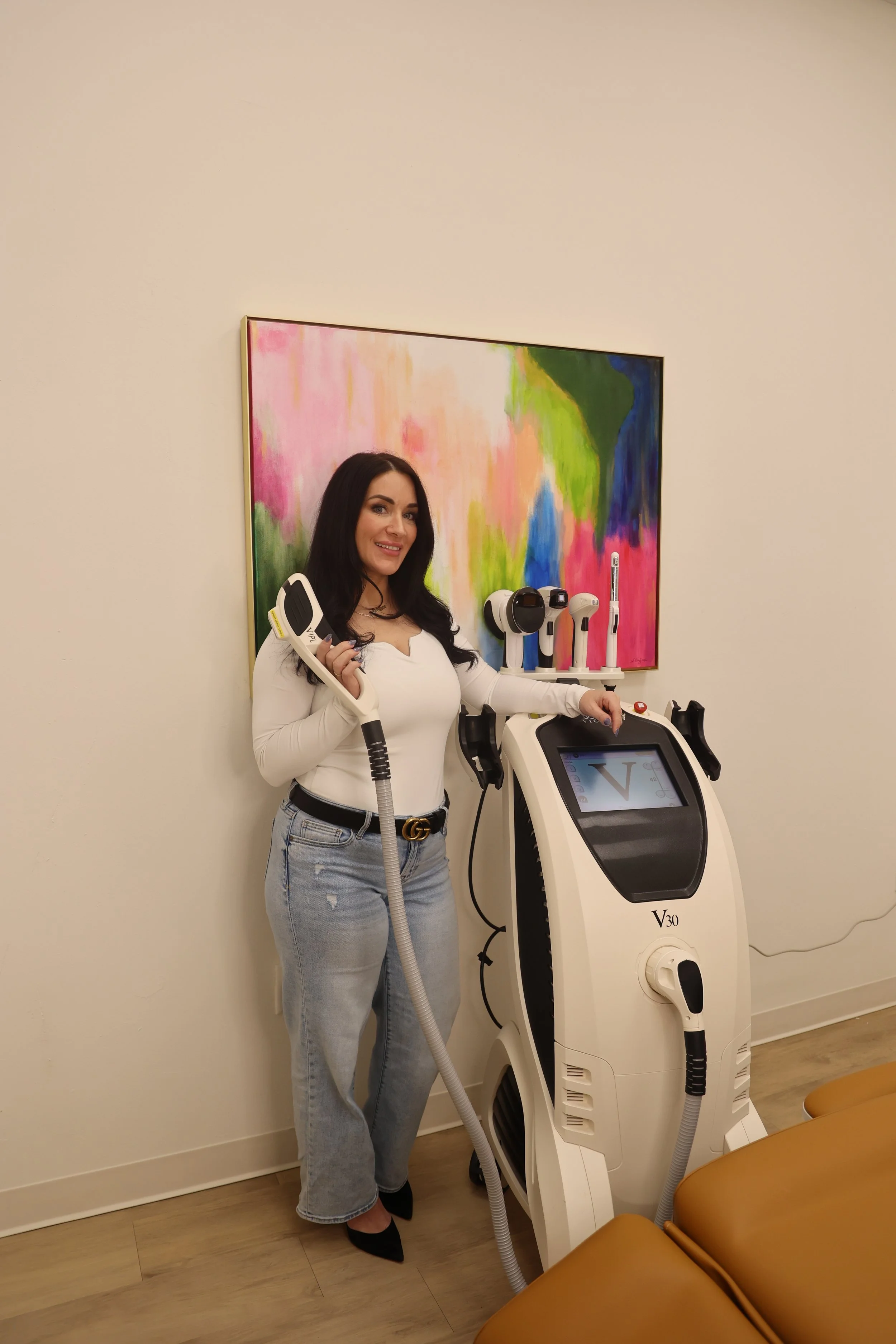 Aesthetician performing a facial treatment with a device on a reclining woman.