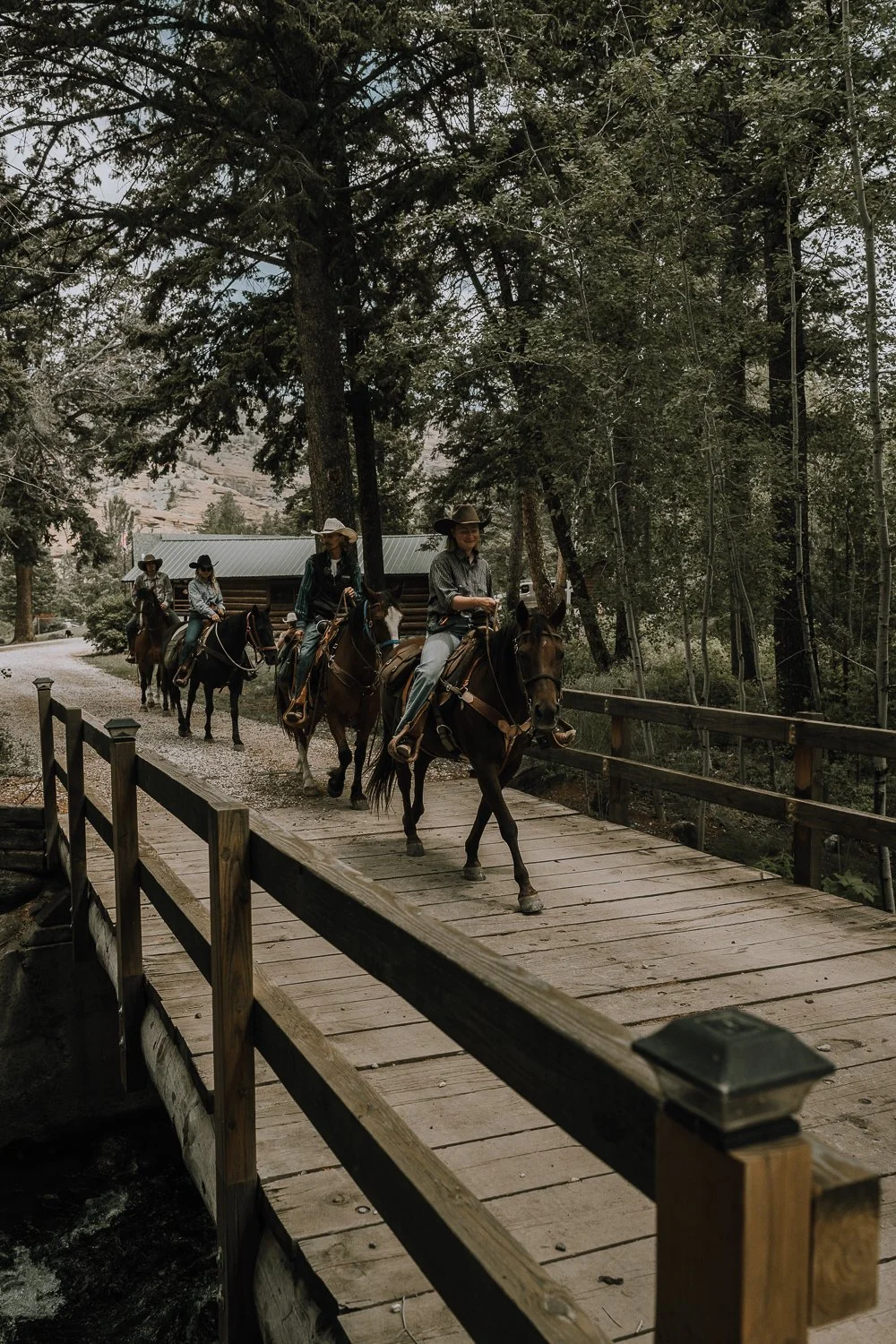 Dude ranch vacationers cross a bridge on horseback at a Wyoming dude ranch.