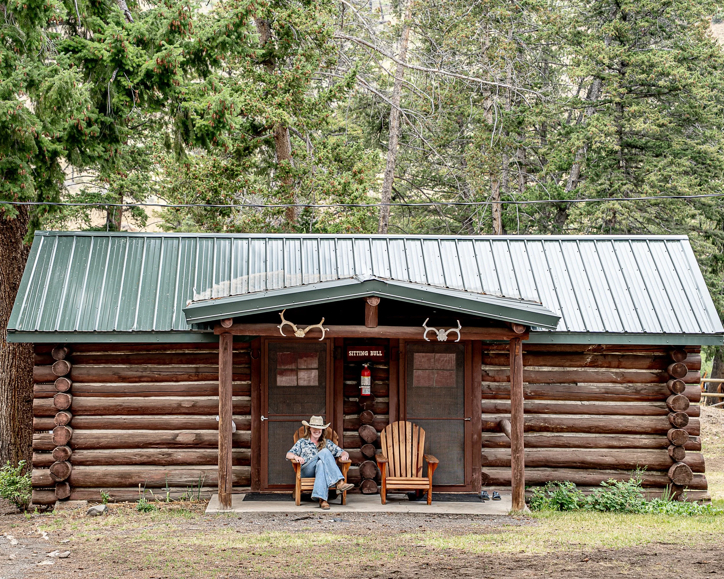 A dude ranch guest sits outside of a historic mountain cabin in Wyoming. 