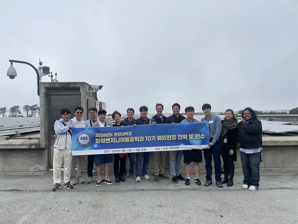 SFPUC Power Staff and Hanyang University students pose in front of solar arrays holding a banner.
