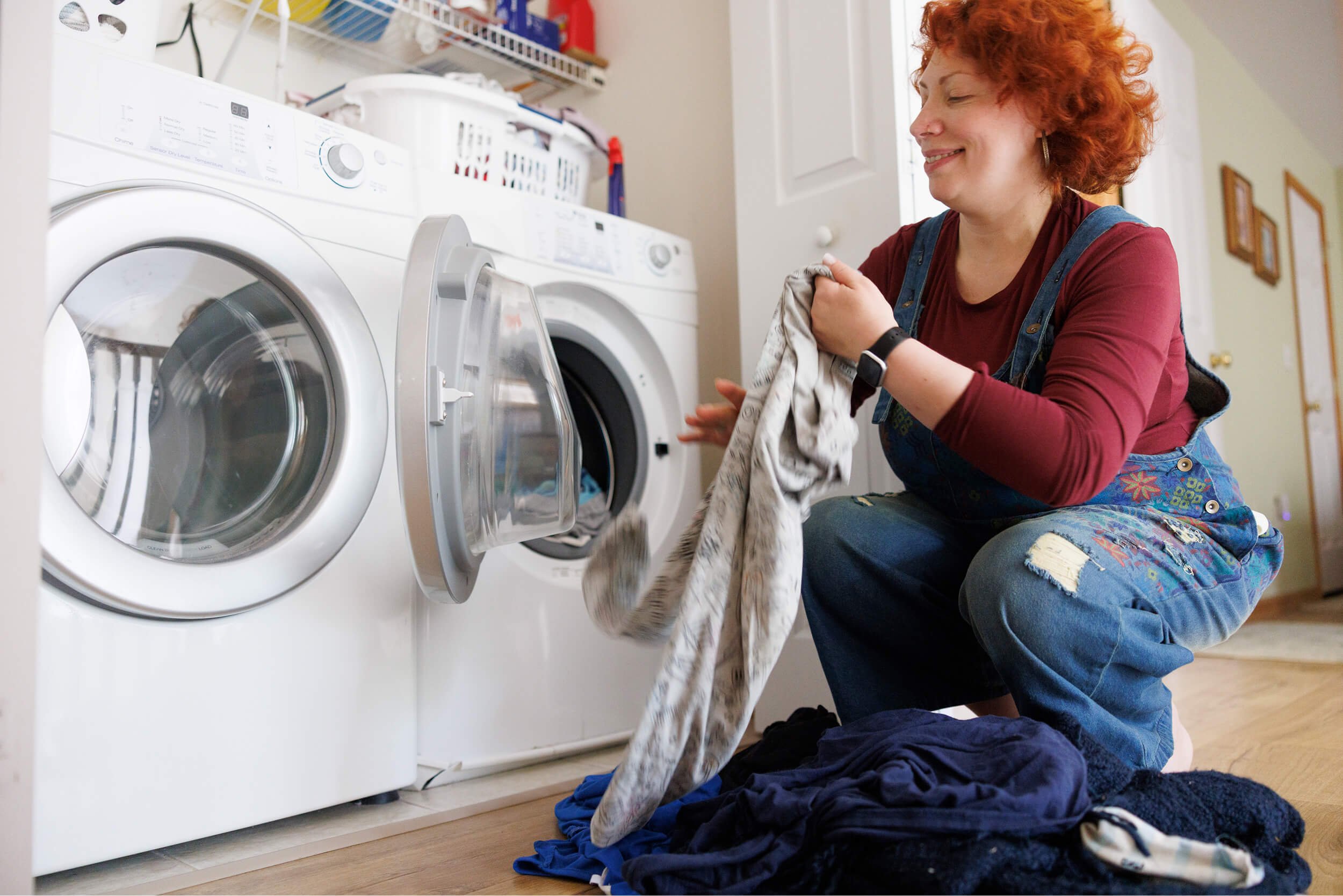 Woman loading clothes into a washing machine.