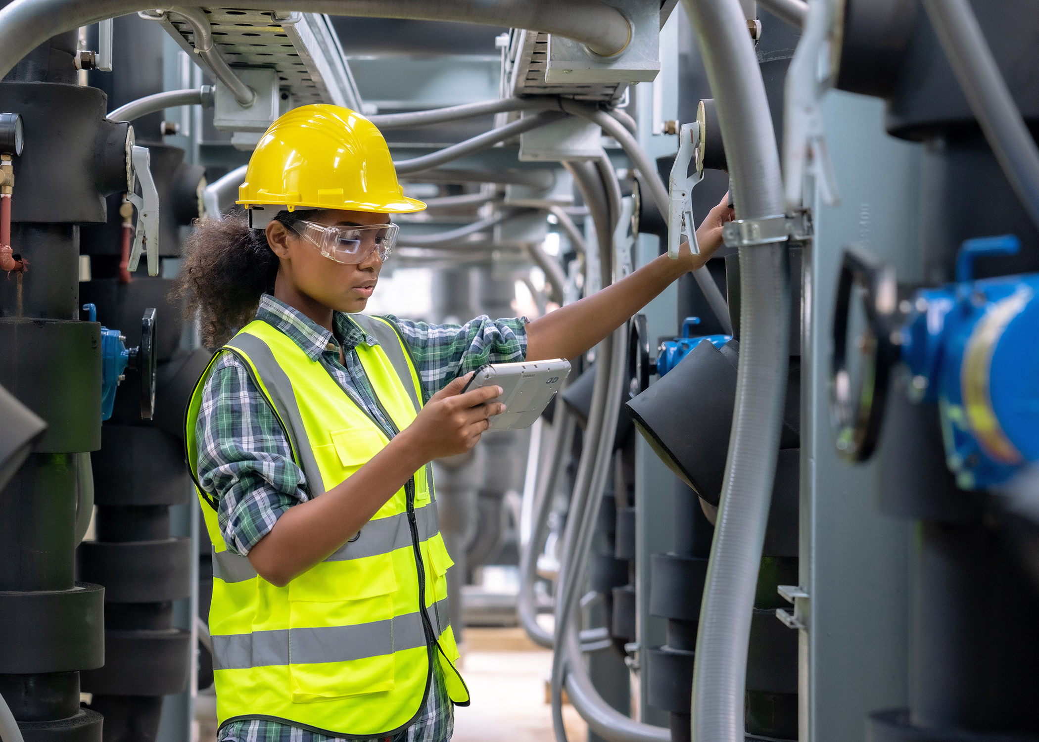 An electrical worker wearing safety gear looking at their notes.