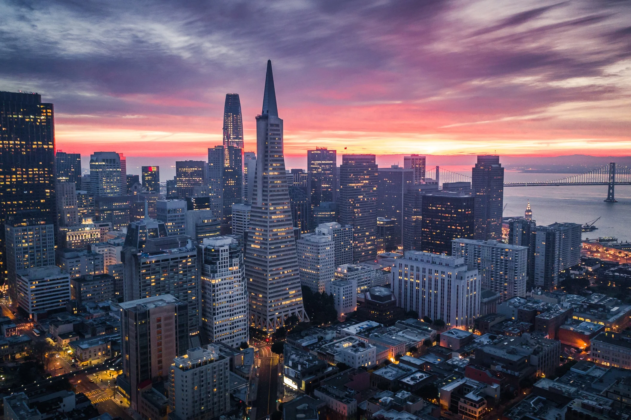 San Francisco skyline at sunset with city lights and bay in view.