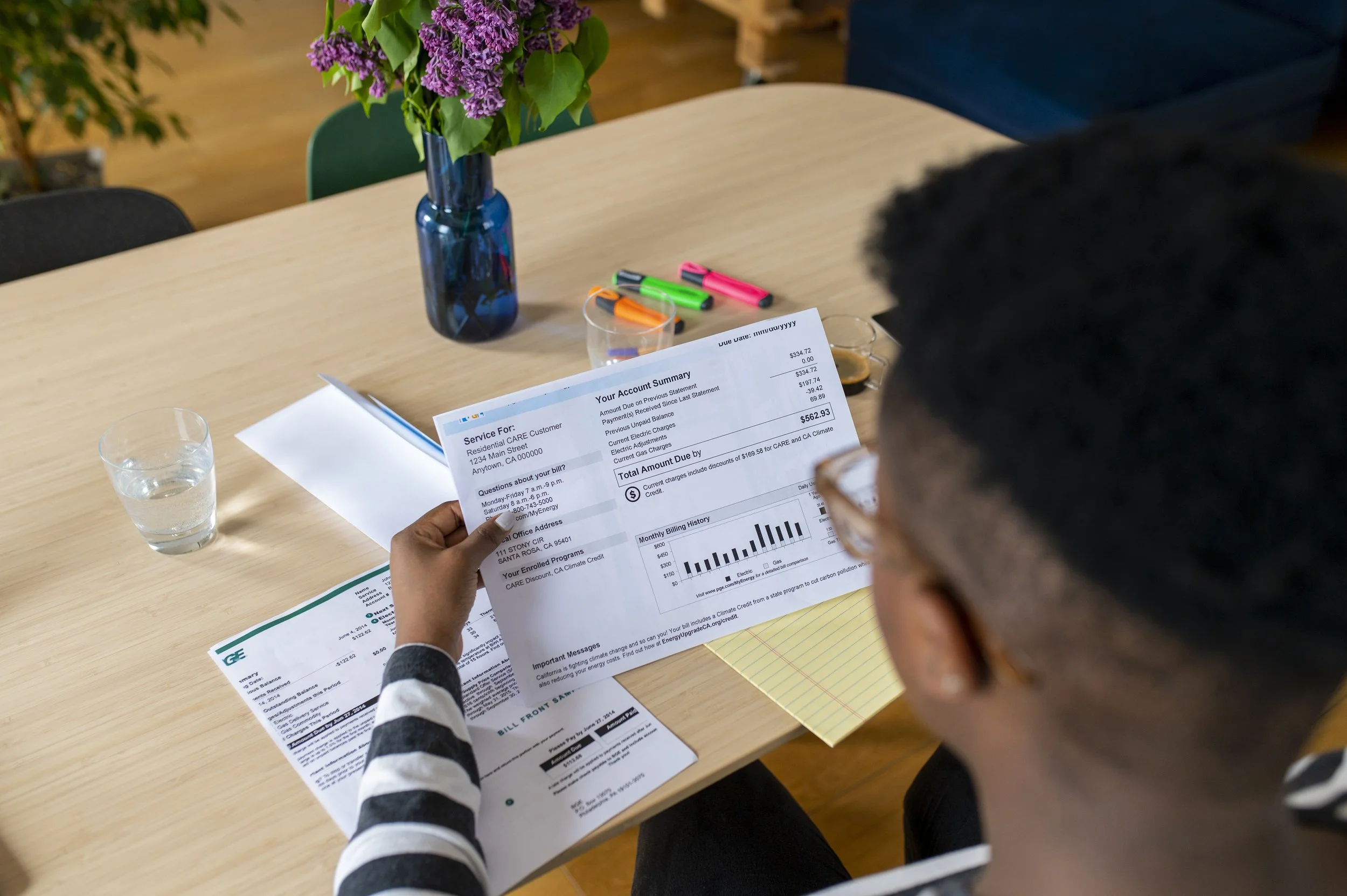 A person sitting at a table reviewing a printed utility bill.