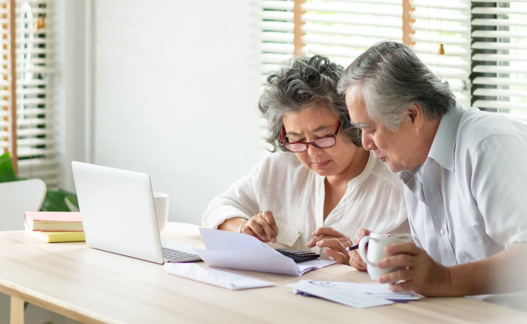 Two people sitting at a table reviewing documents together with a laptop nearby.