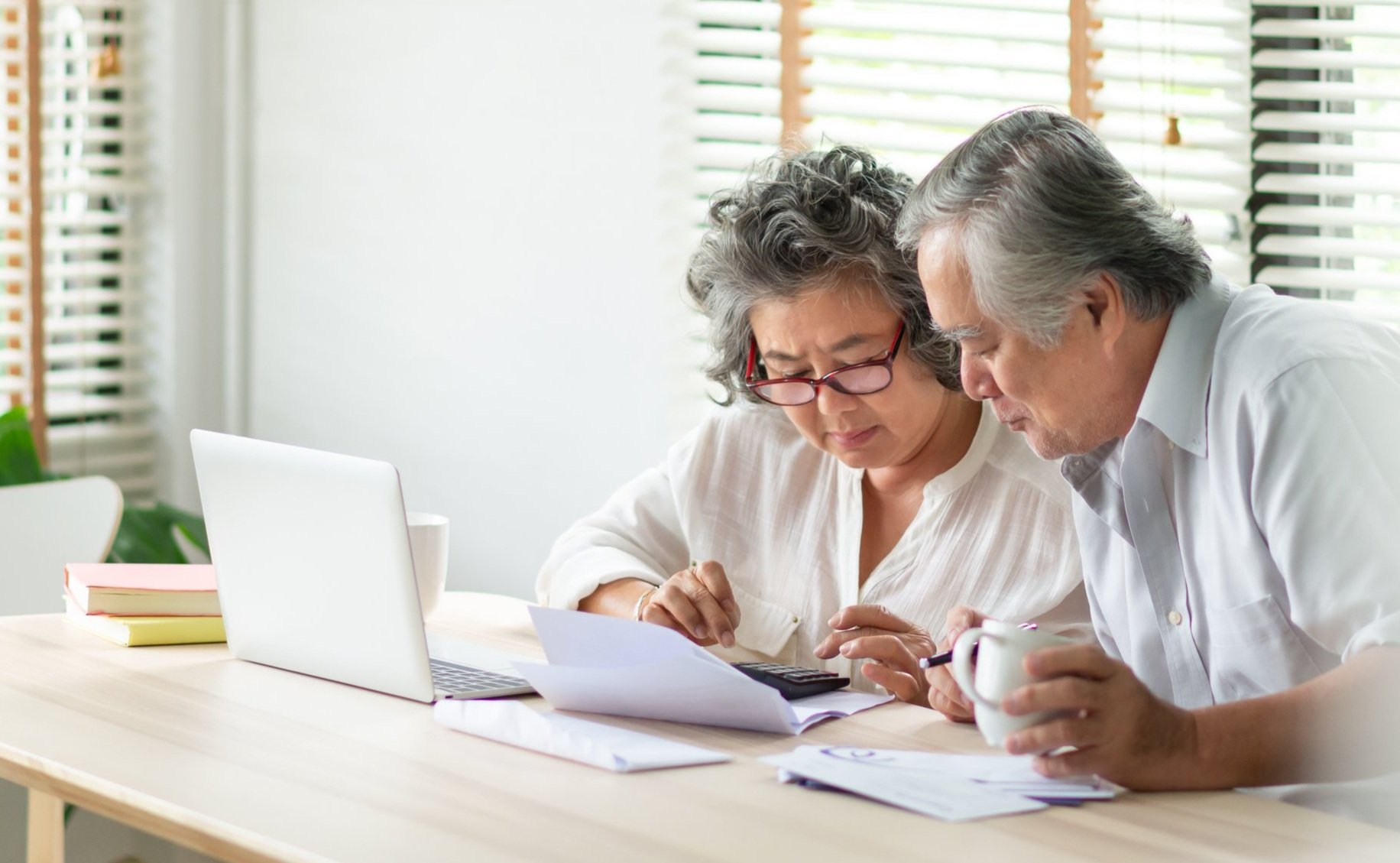 Two people sitting at a table reviewing documents together with a laptop nearby.