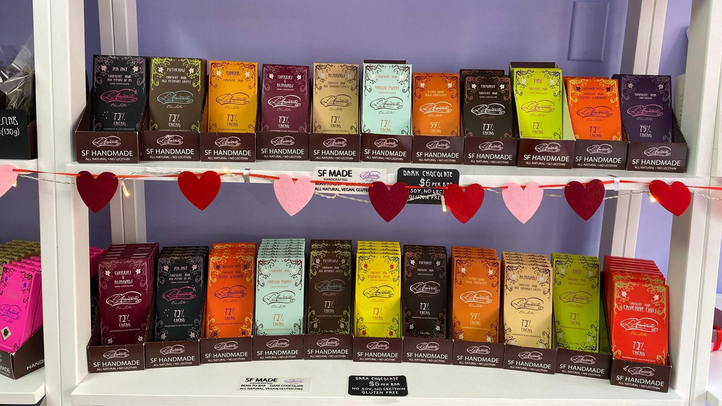 Shelves displaying a variety of boxed chocolates with heart‑themed decorations.