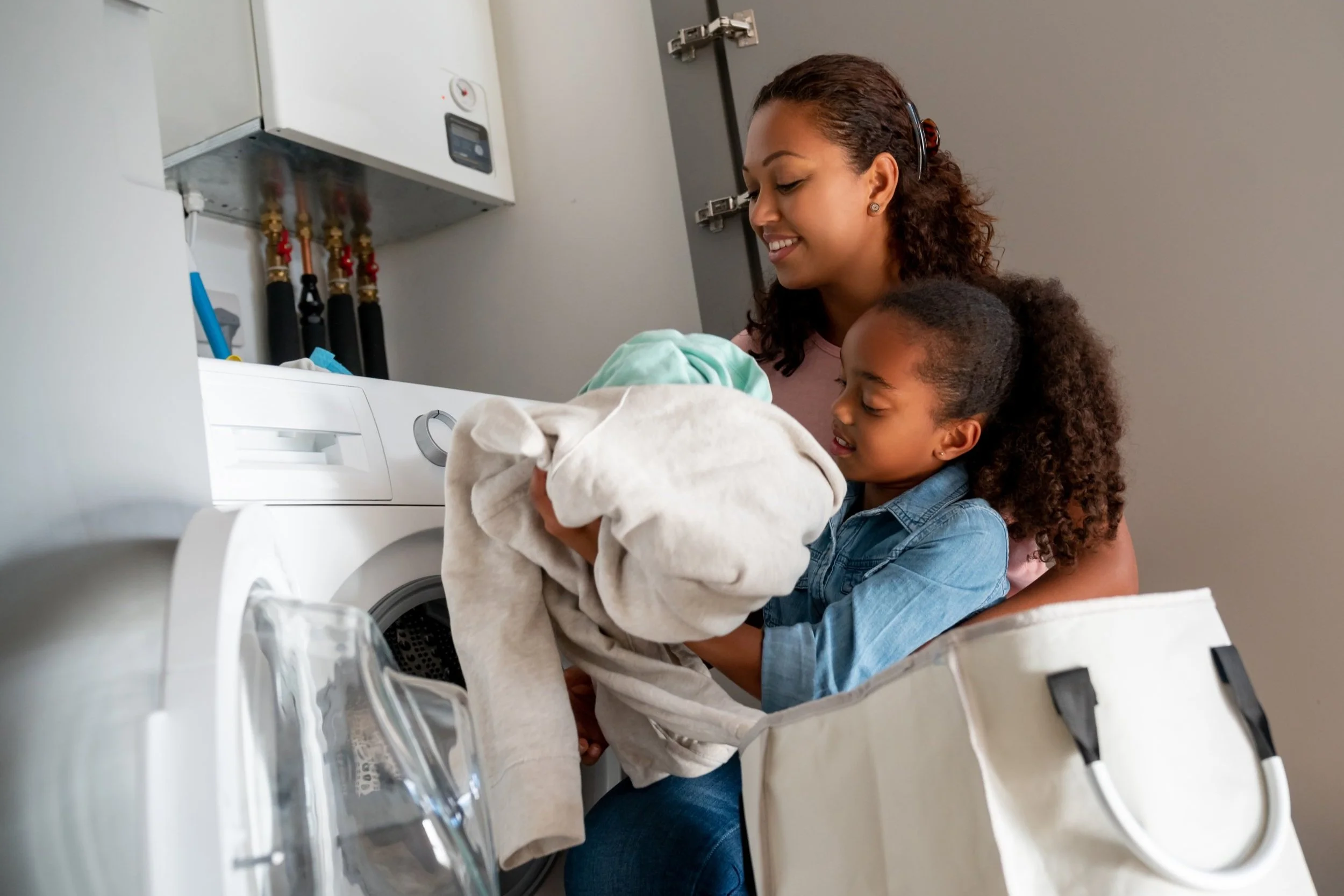 Adult and child loading clothes into a front‑loading washing machine.