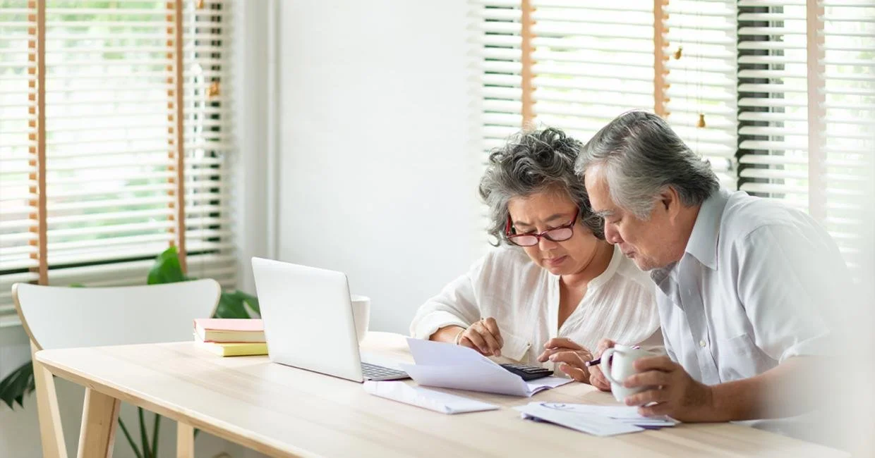 Two people sitting at a table reviewing documents together with a laptop nearby.