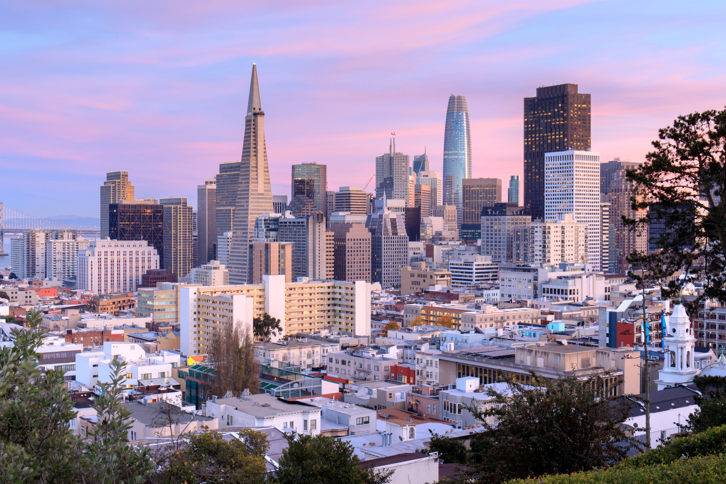 San Francisco skyline at sunset with city lights and bay in view.