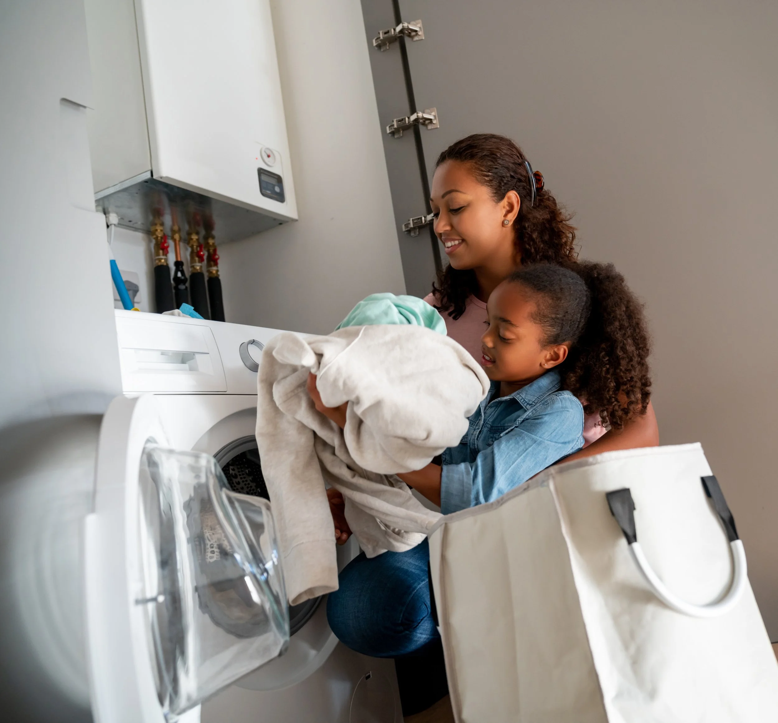A parent and their child putting laundry into the washing machine.