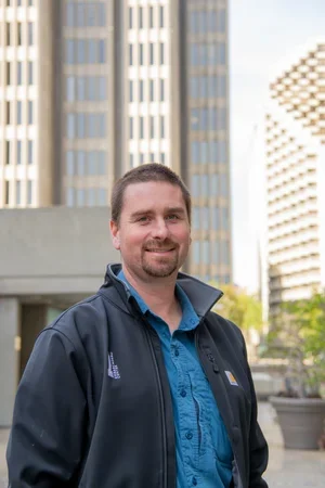  A person smiling in front of buildings.&nbsp; 