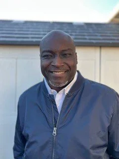  A person smiling in front of a building.&nbsp; 