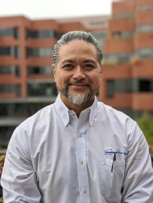  A person smiling in front of red bricked buildings. 