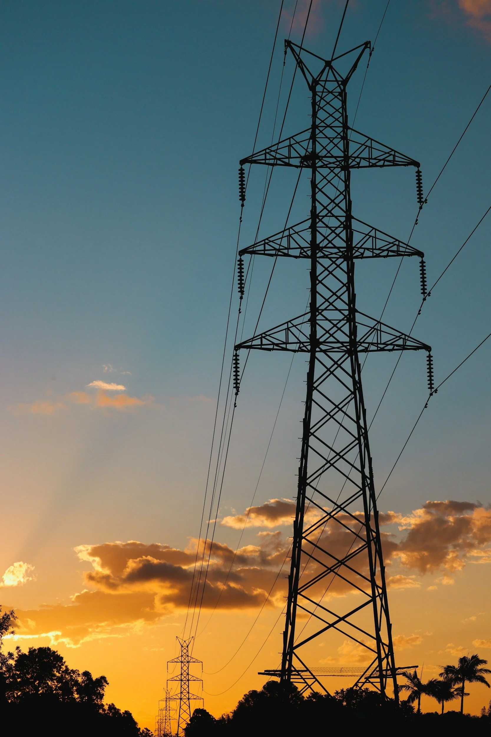 High-voltage power lines and transmission tower at sunset.