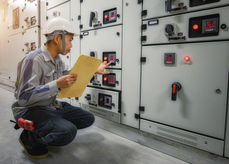 An electric worker wearing safety gear pressing a button.