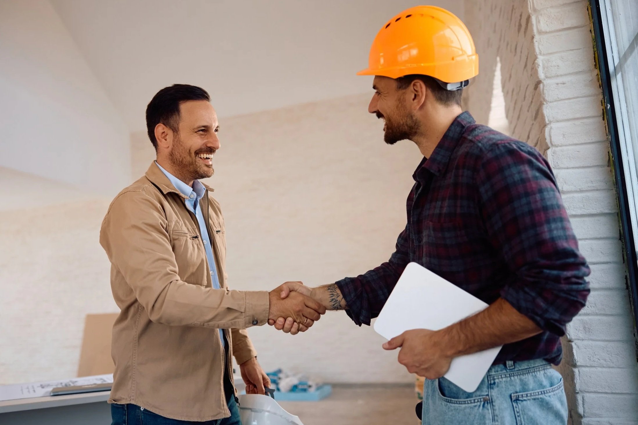 Two smiling contractors shaking hands
