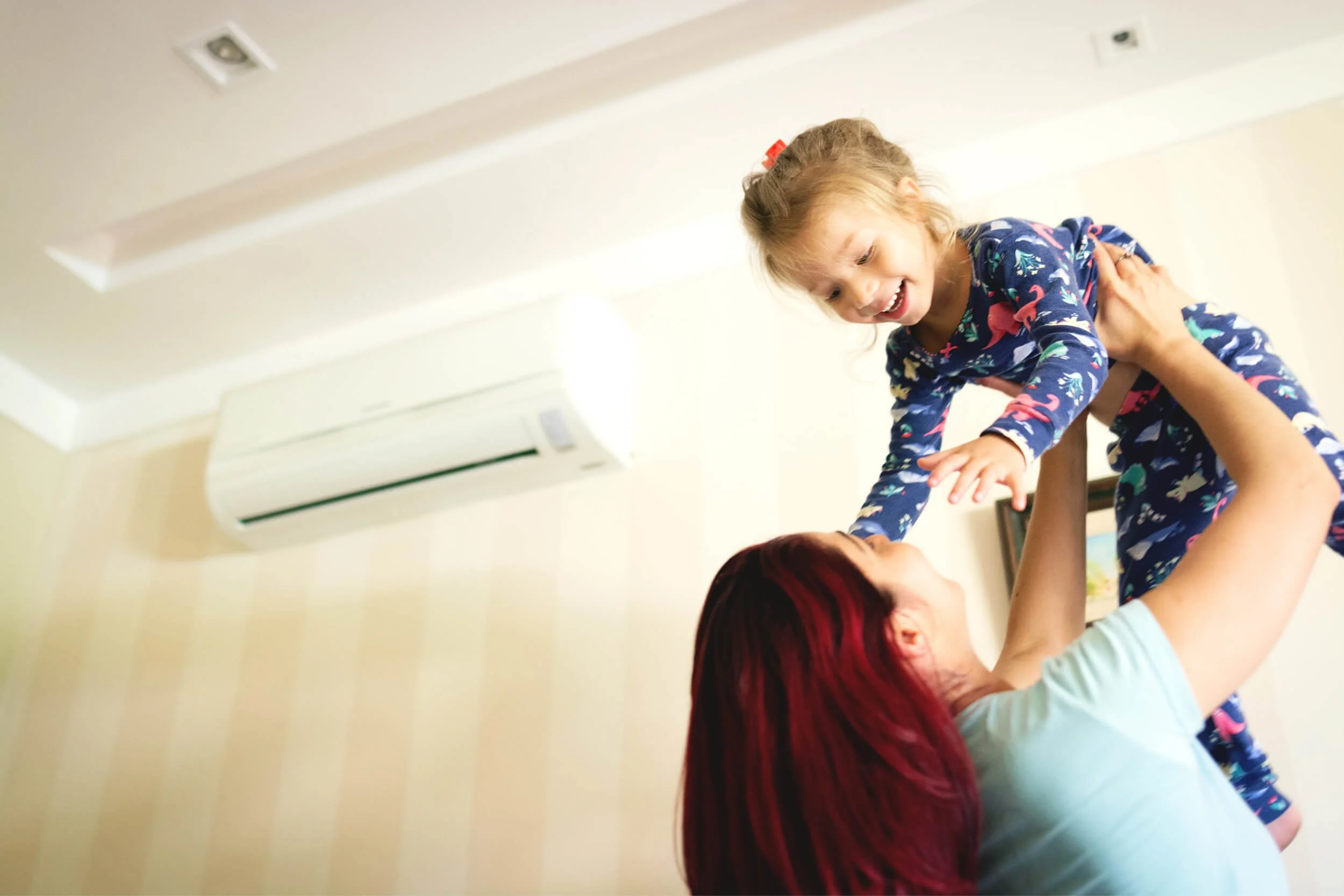 A child being lifted by their parent in a room.