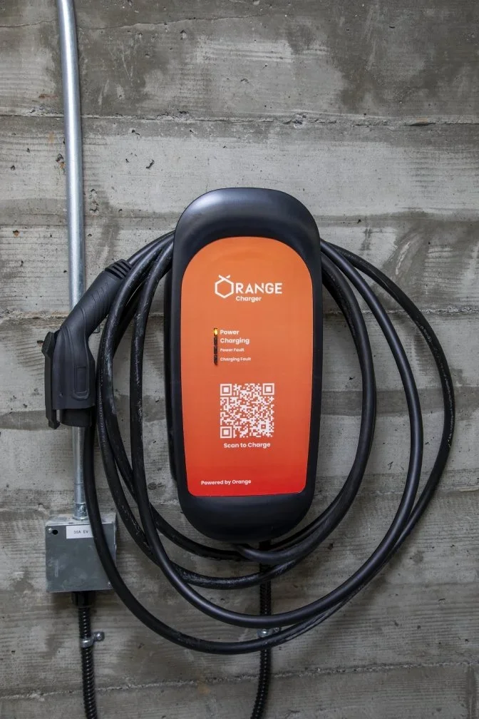 Wall-mounted electric vehicle charger with coiled cable.