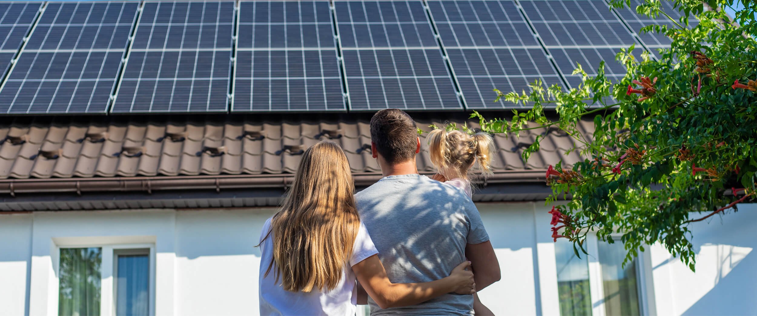 A family looking at solar panels that are installed on a home’s roof.