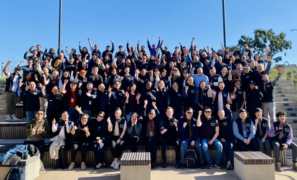 A group of people outside posing with their hands up.