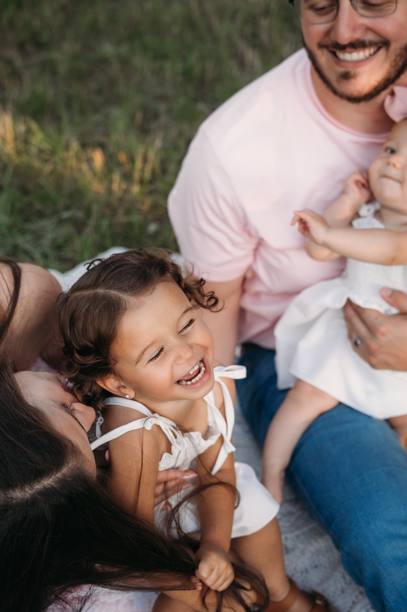 family laughing together on blanket during outdoor family session The Woodlands TX