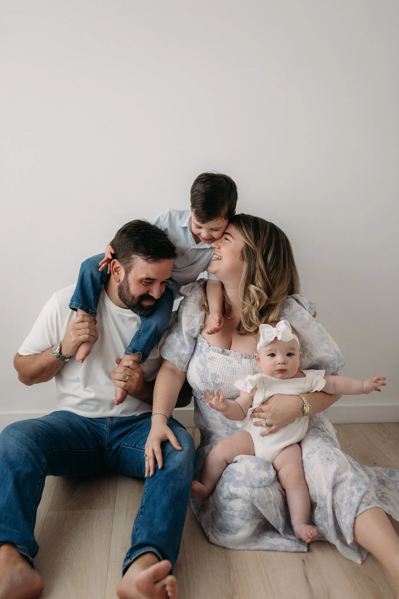 family of four laughing and playing together during studio family session Houston TX