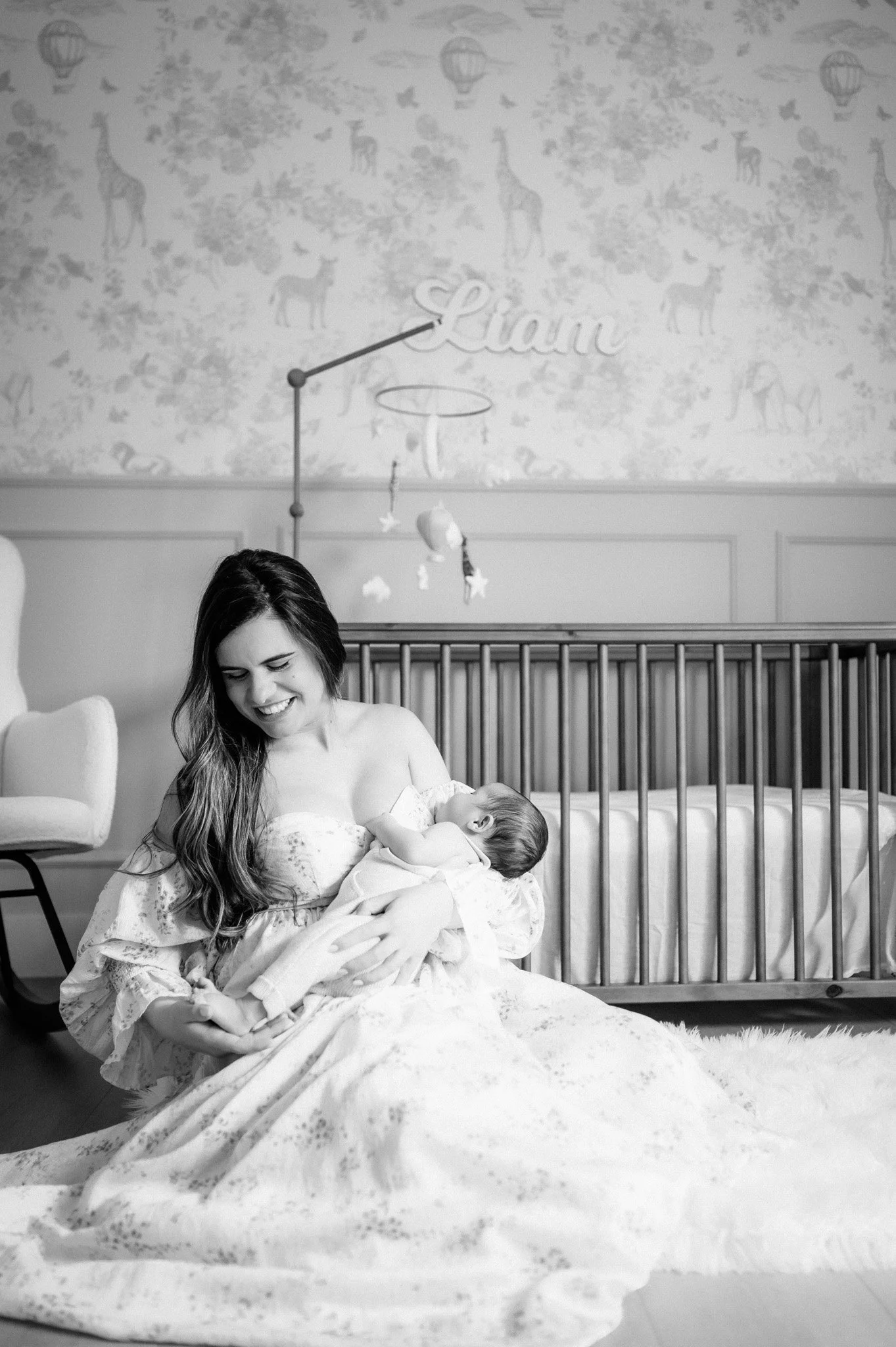black and white photo of mother nursing newborn baby in nursery during in-home newborn session Houston TX