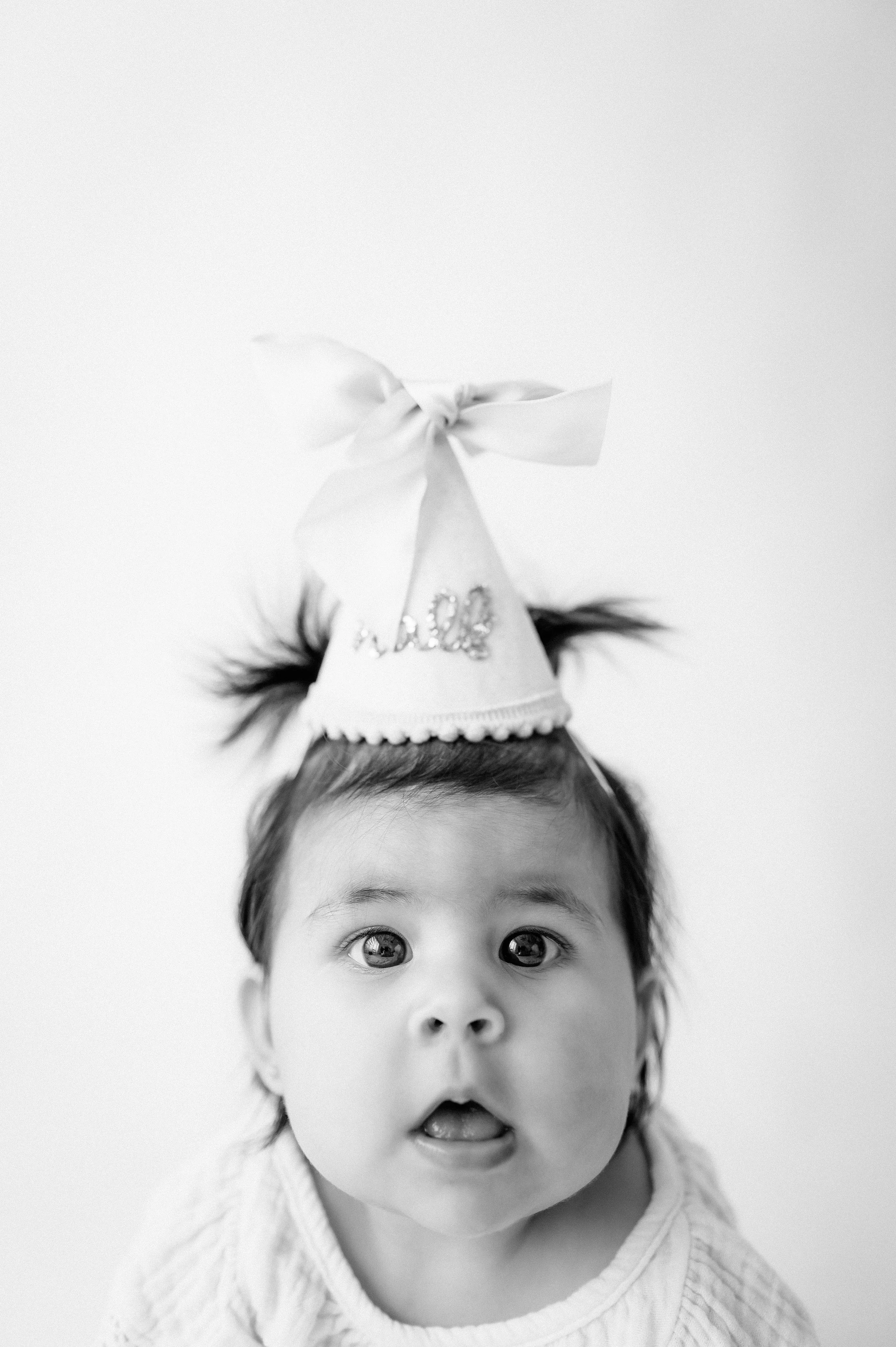 black and white close up of baby wearing first birthday party hat during cake smash session Houston TX