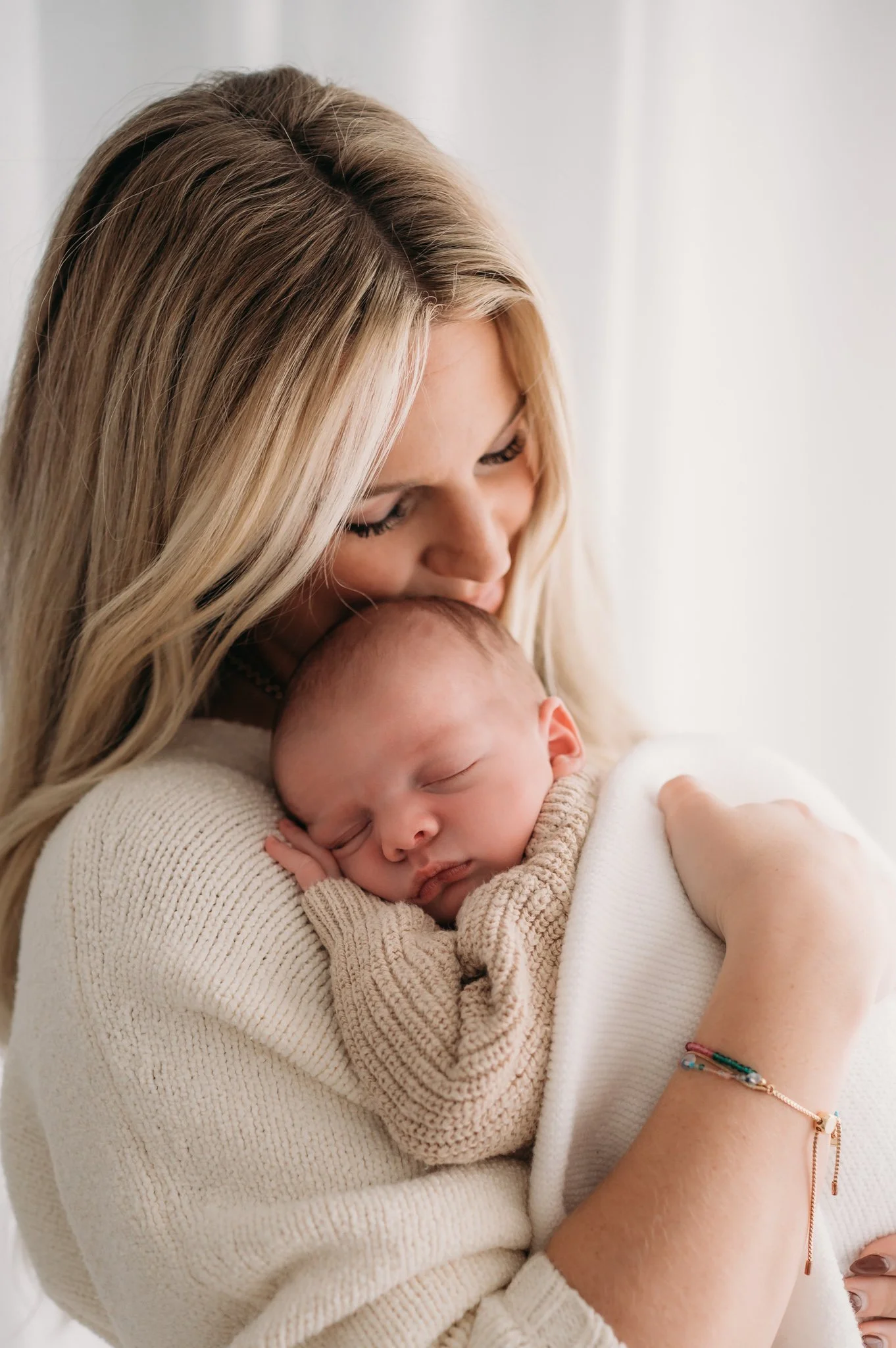 mother holding sleeping newborn baby close during studio newborn session Houston TX