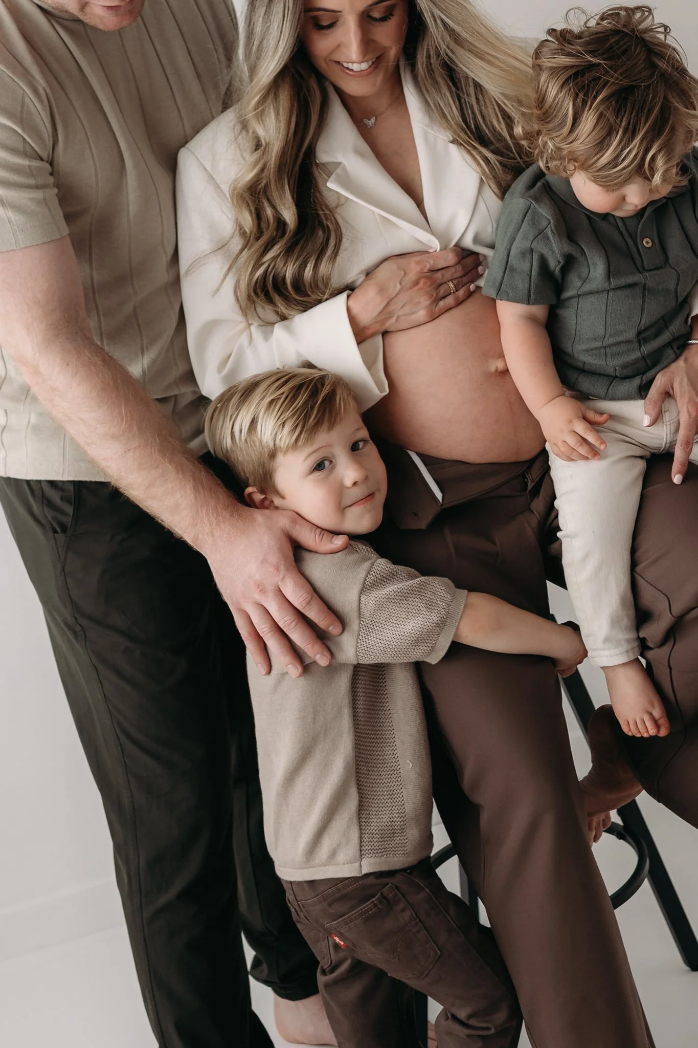 pregnant mother poses with her family showing off her bump in houston, texas maternity photography studio