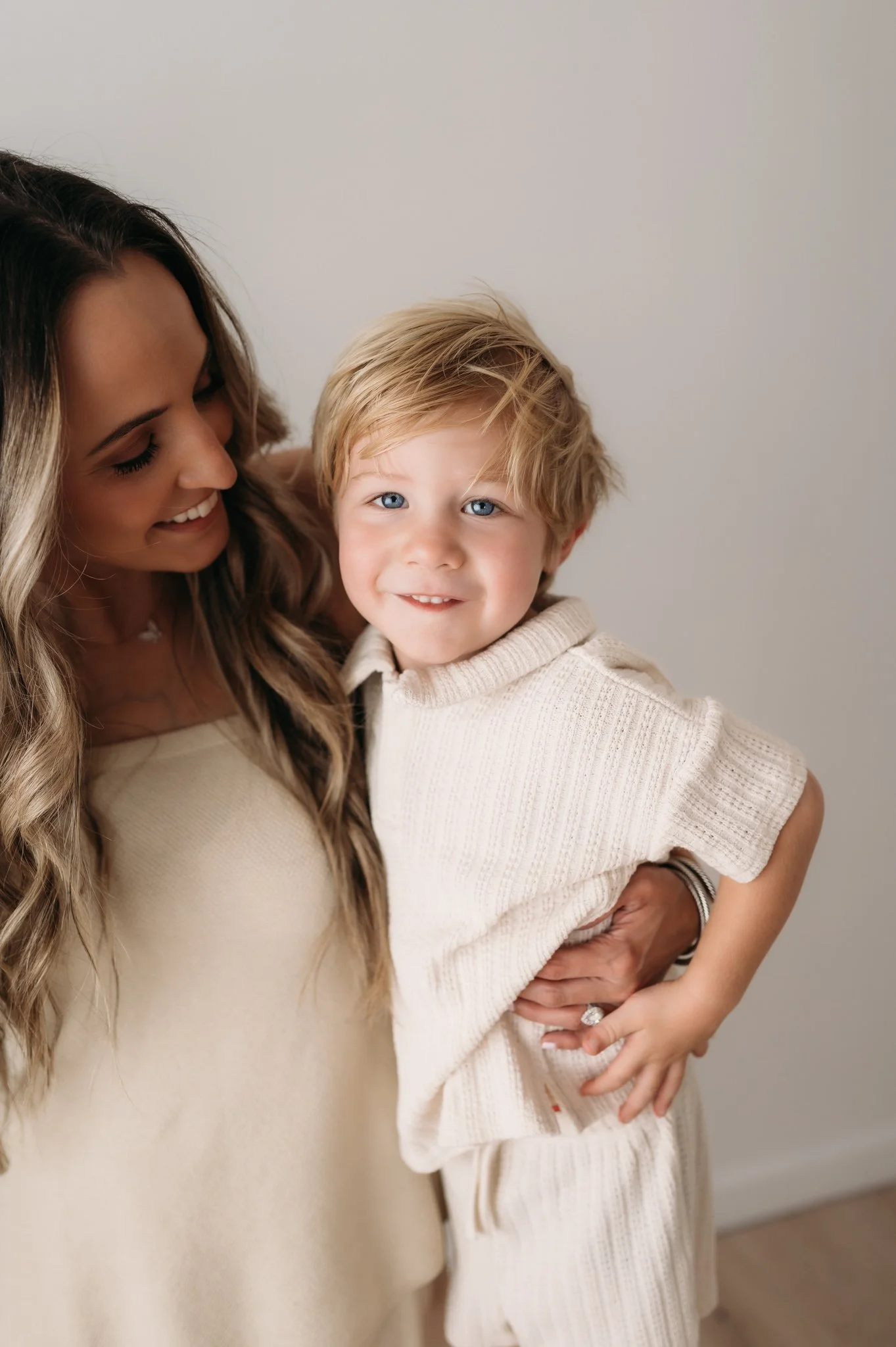 mother smiling at toddler boy during studio family session Houston TX