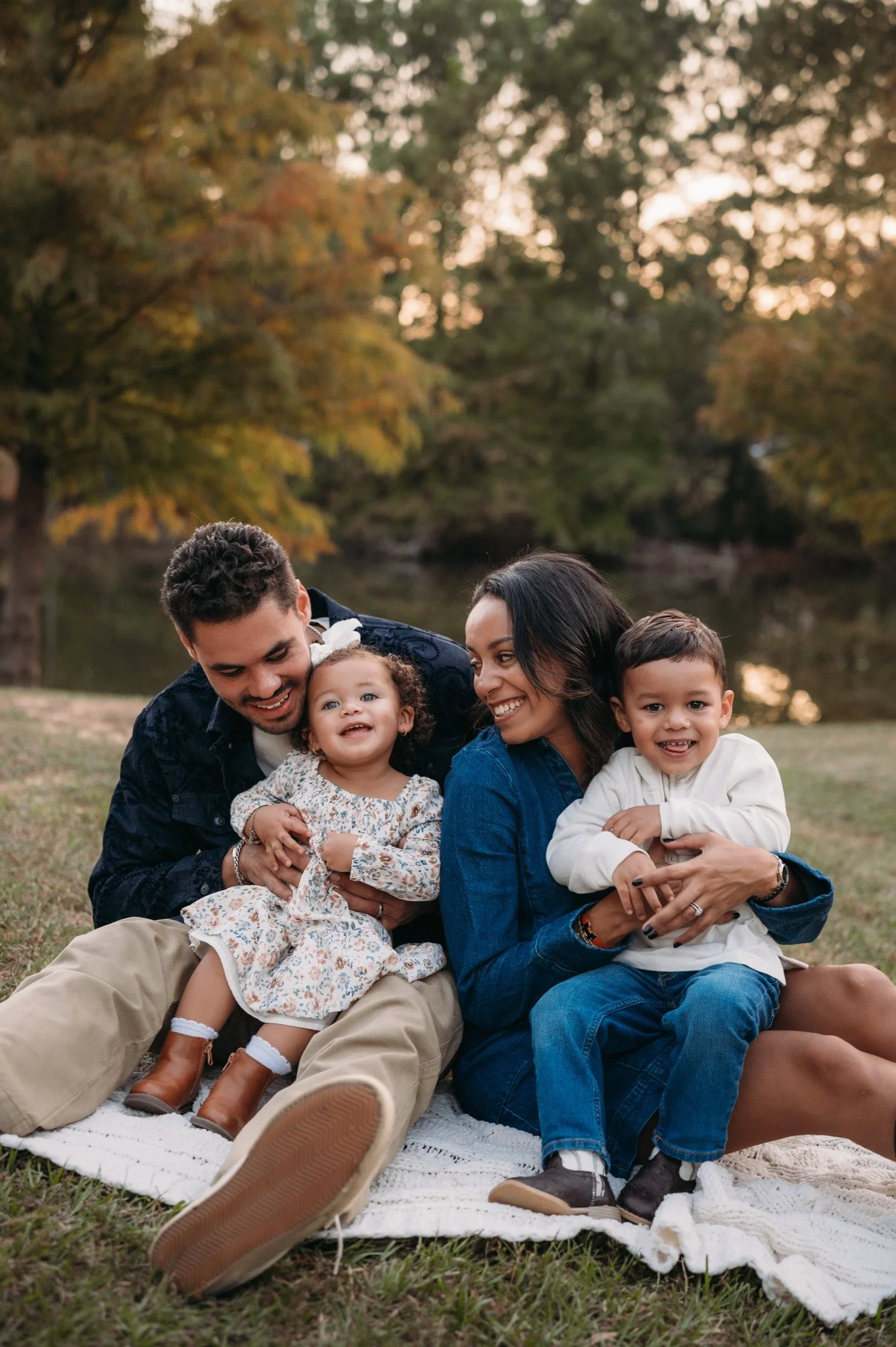 family of four sitting together laughing during outdoor fall family session Houston TX