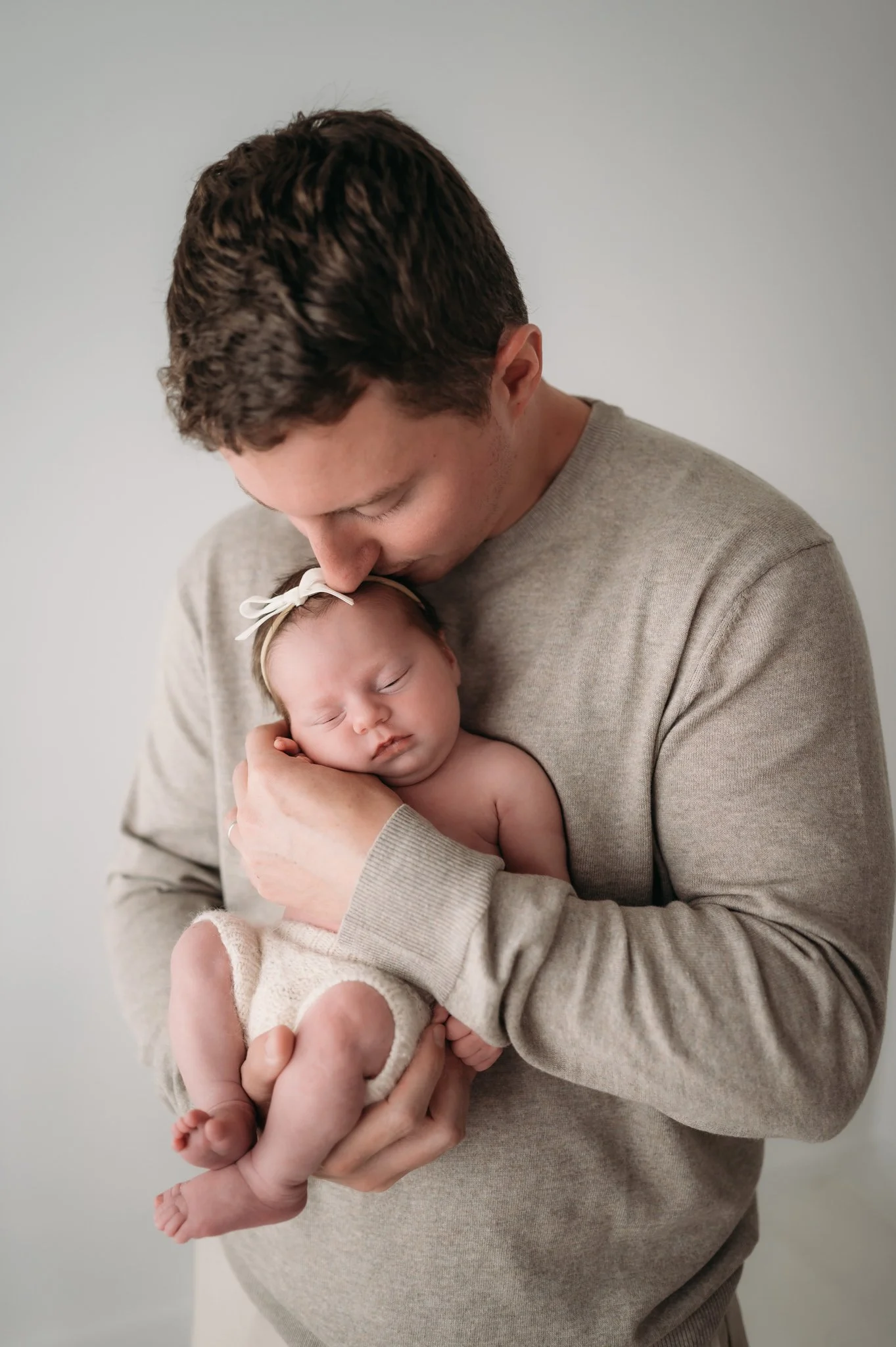 father cradling sleeping newborn baby during studio newborn session Houston TX