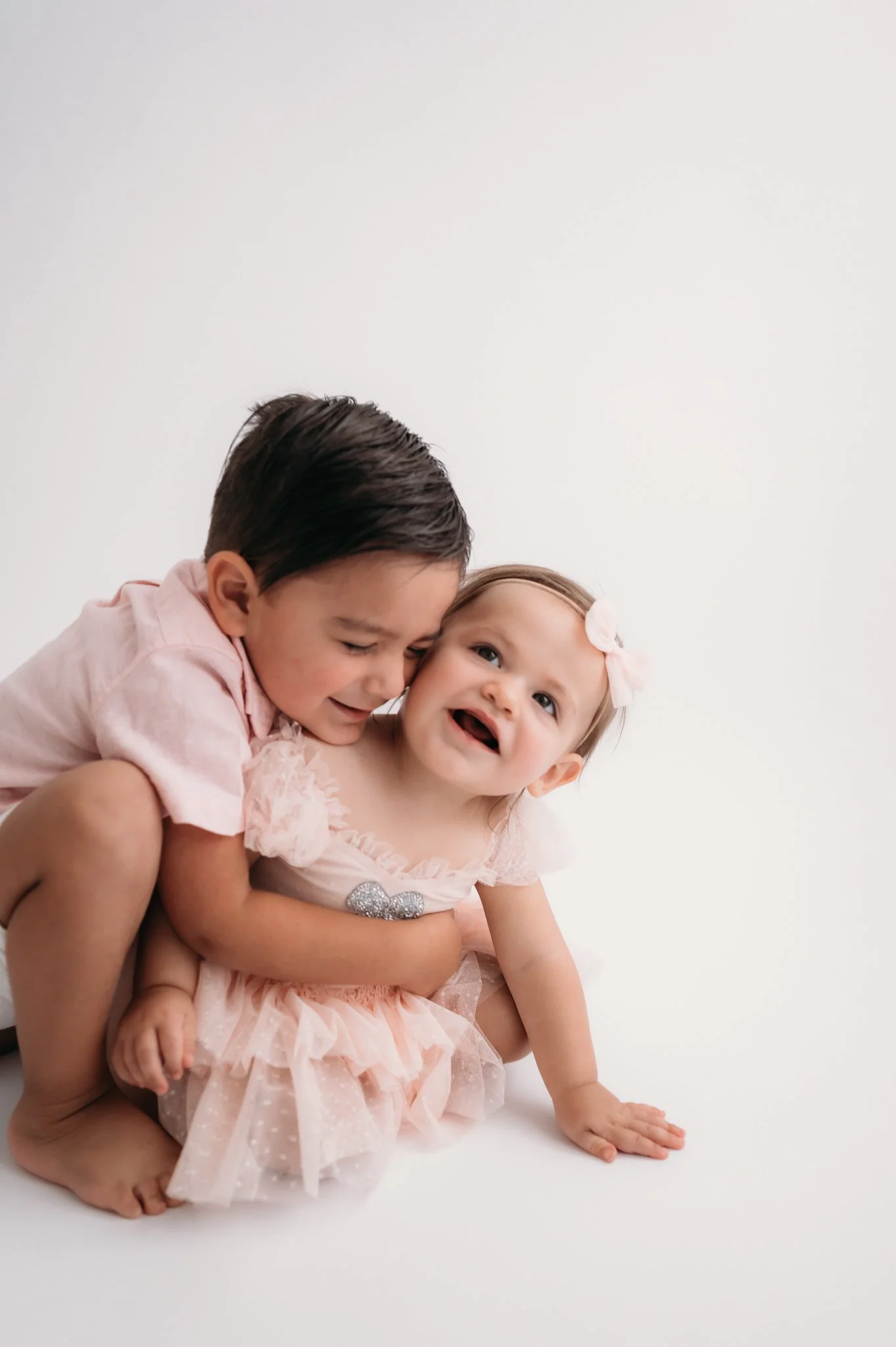 toddler hugging laughing baby sister during studio milestone session The Woodlands TX