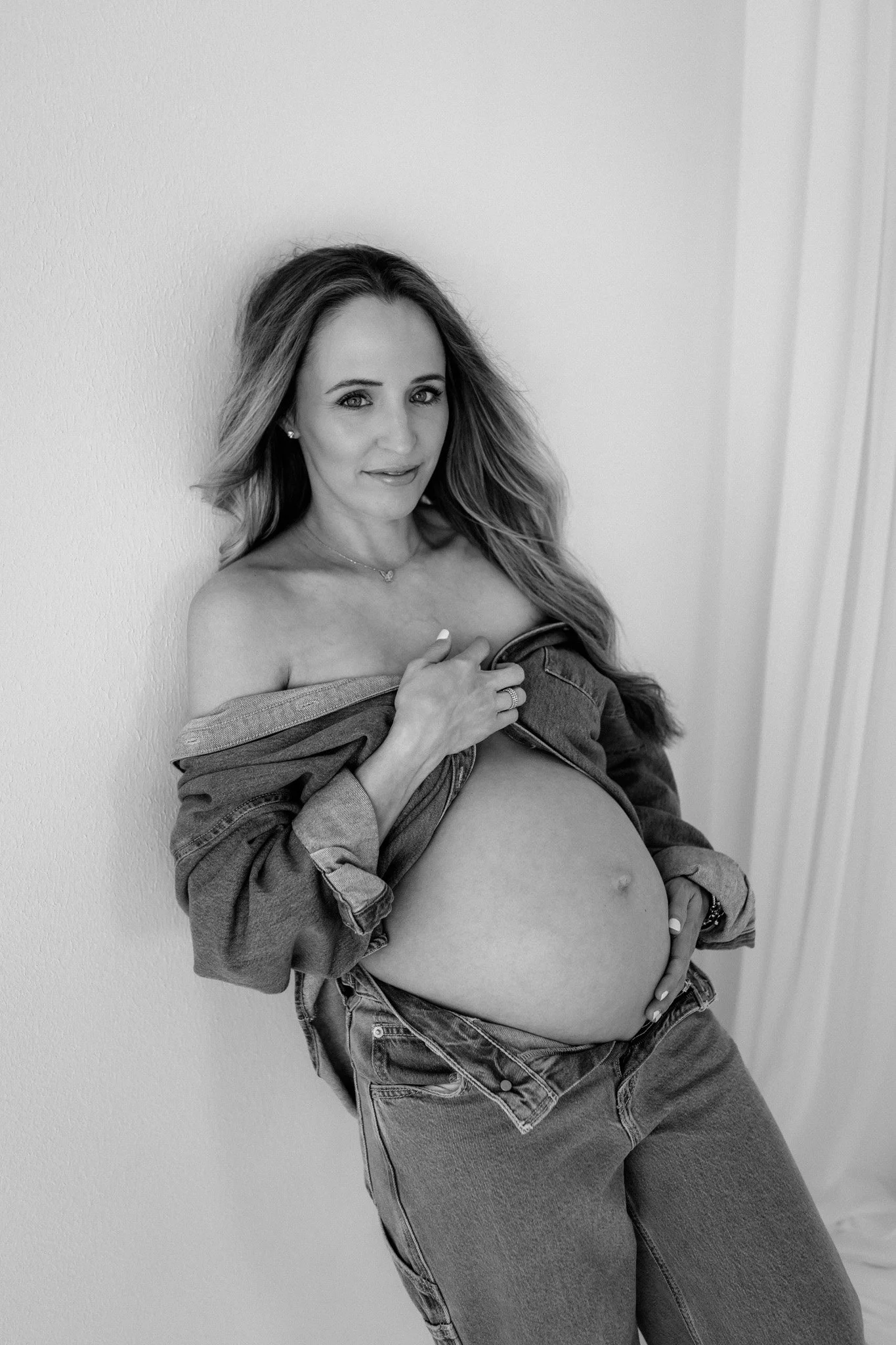 mom in all denim poses during her maternity photography session in the woodlands, texas