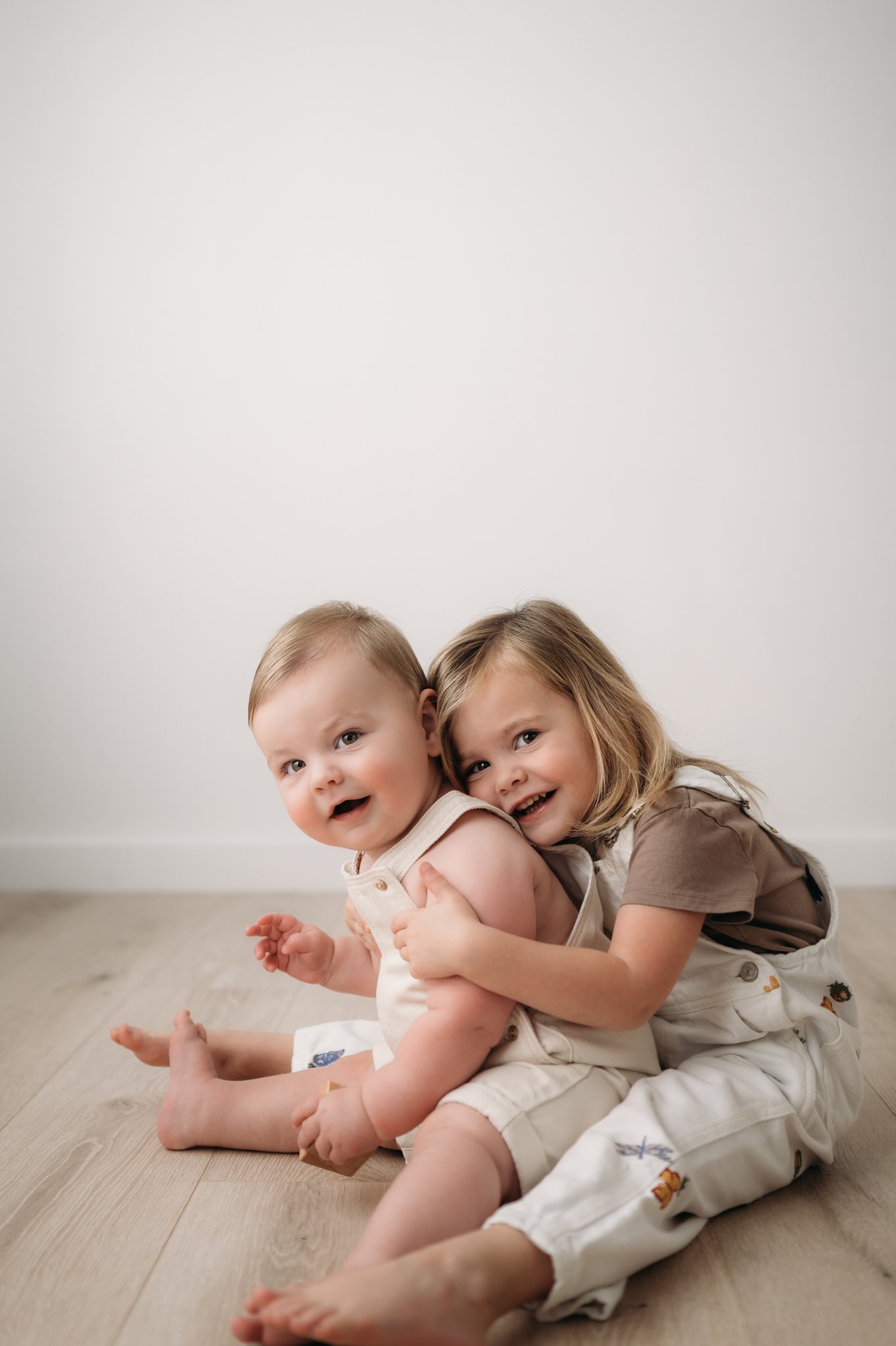 two toddler siblings laughing together during studio milestone session The Woodlands TX