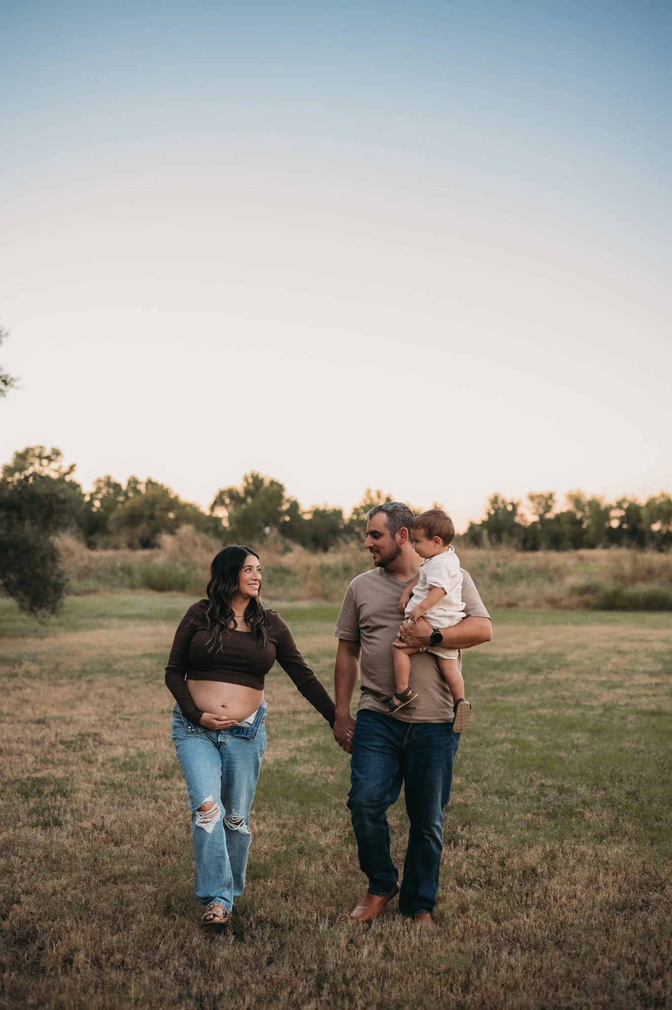 family walking together in open field during outdoor maternity session The Woodlands TX