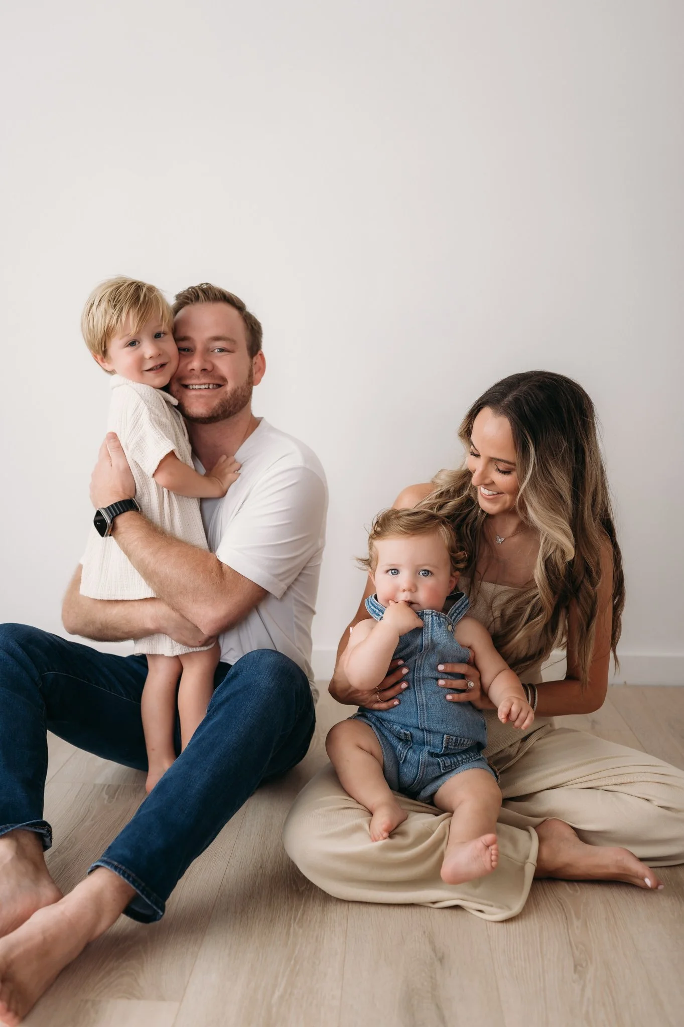 family of four sitting on studio floor with toddler and baby during family session The Woodlands TX
