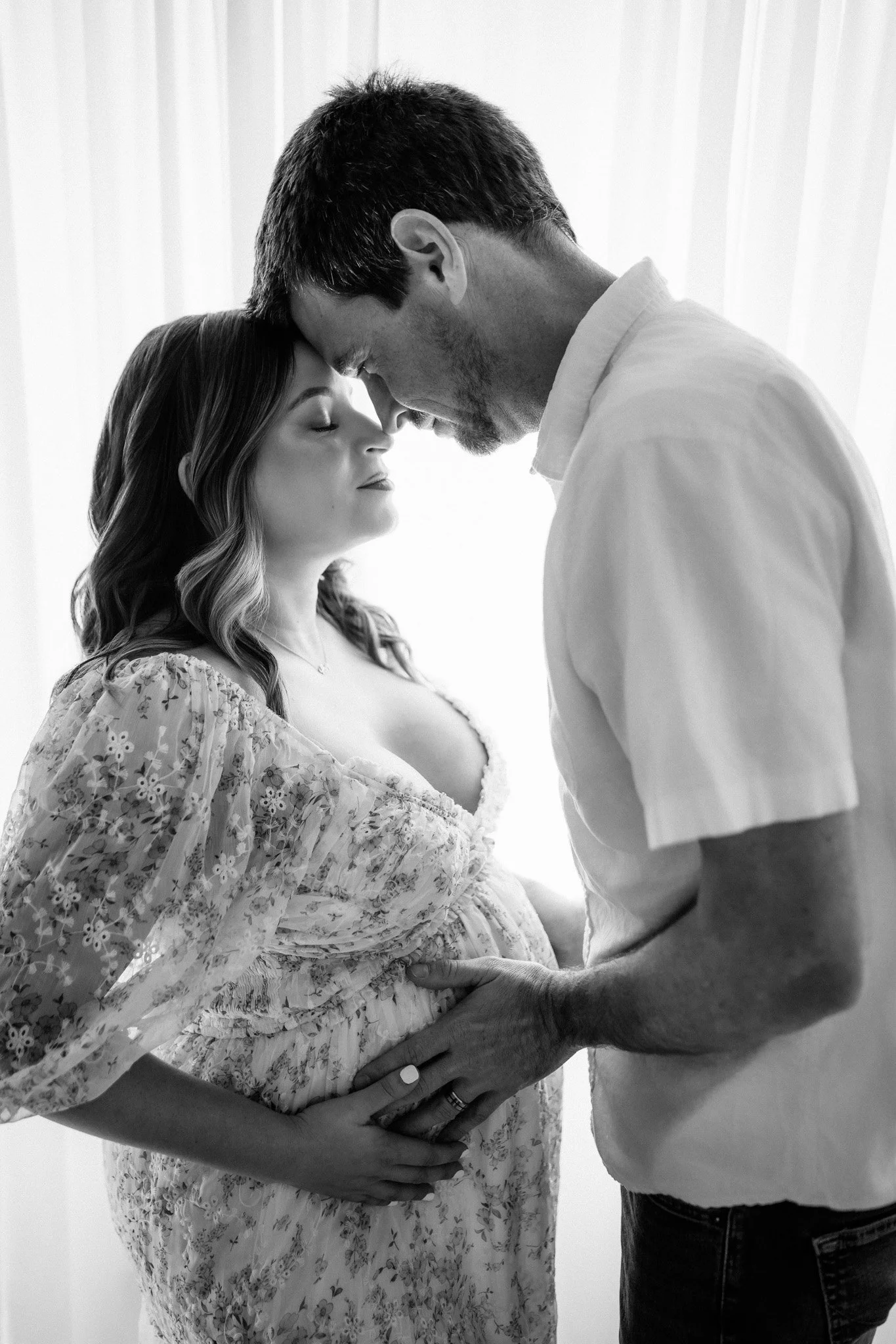 black and white photo of couple embracing and cradling pregnant belly during maternity session Houston TX