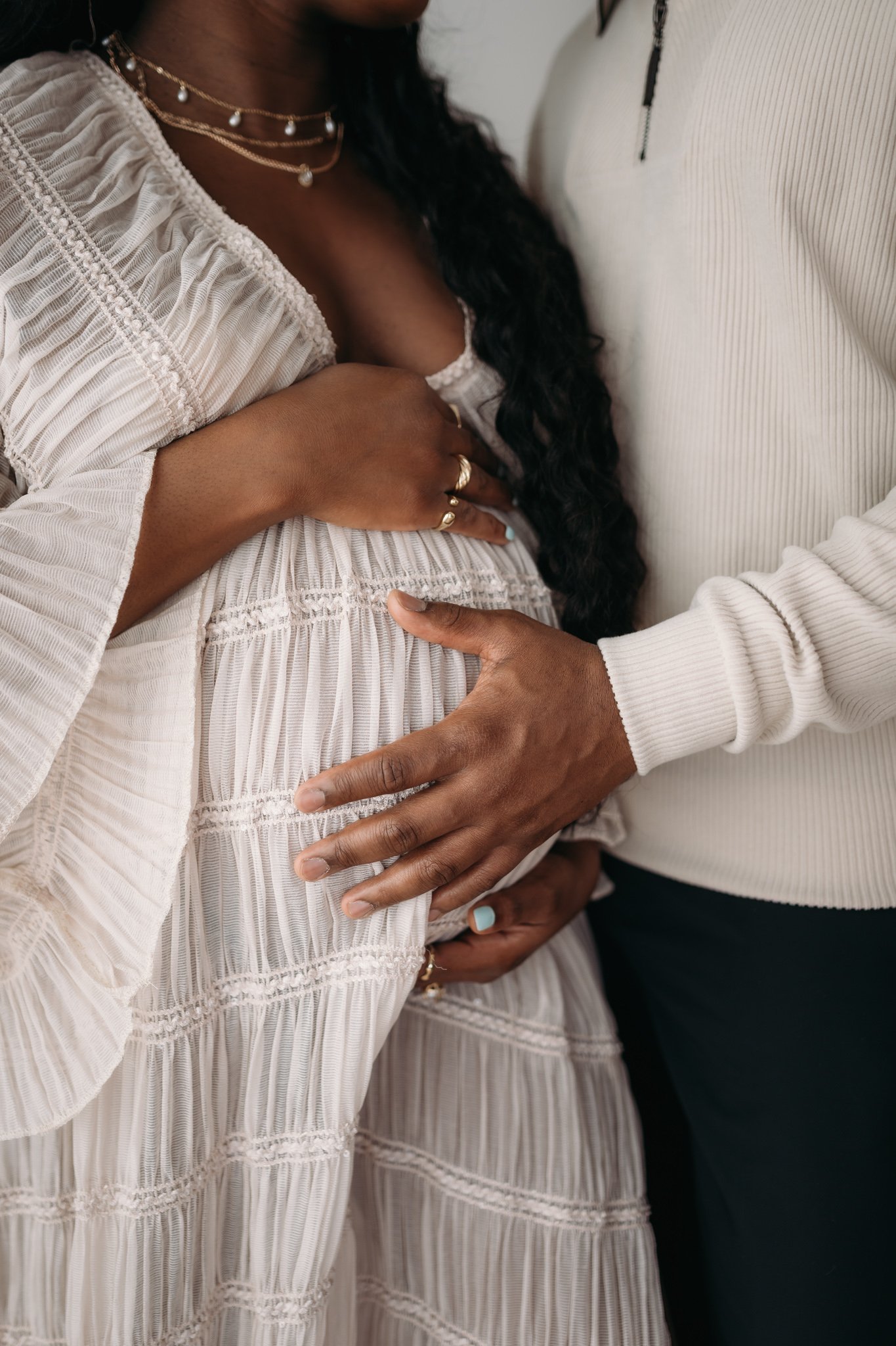 close up of partner embracing pregnant mother's bump during maternity session The Woodlands TX