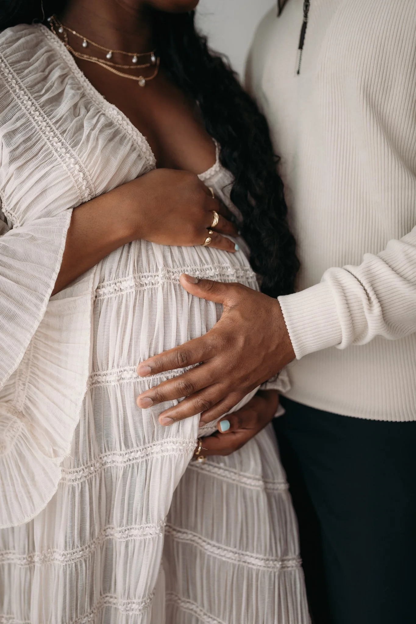 close up of partner embracing pregnant mother's bump during maternity session The Woodlands TX