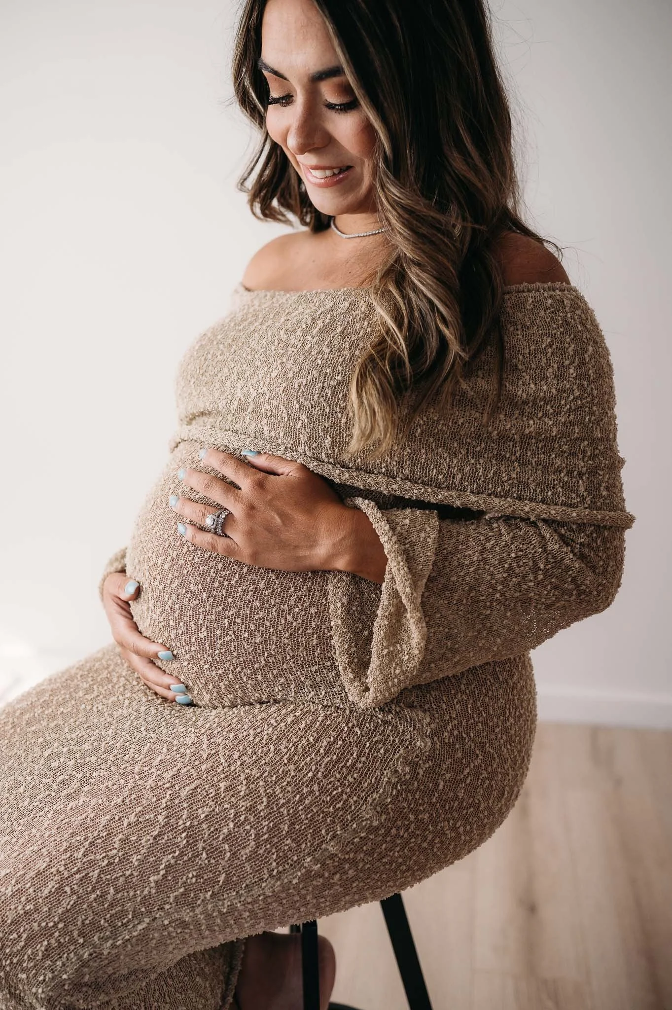 close up of pregnant mother in textured knit dress cradling baby bump during maternity session The Woodlands TX