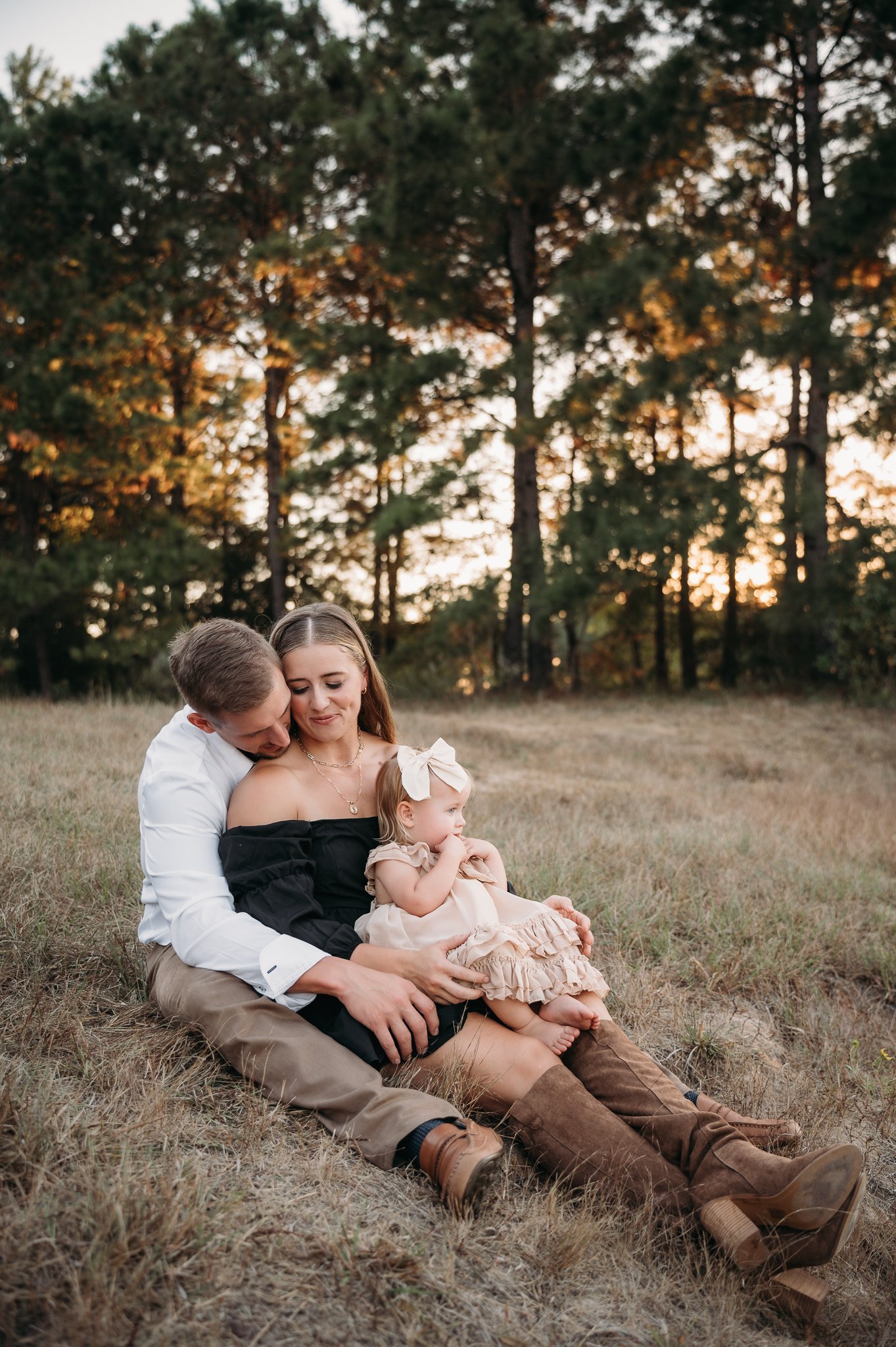 mom, dad and baby snuggle close for family pictures outdoors in the woodlands, texas