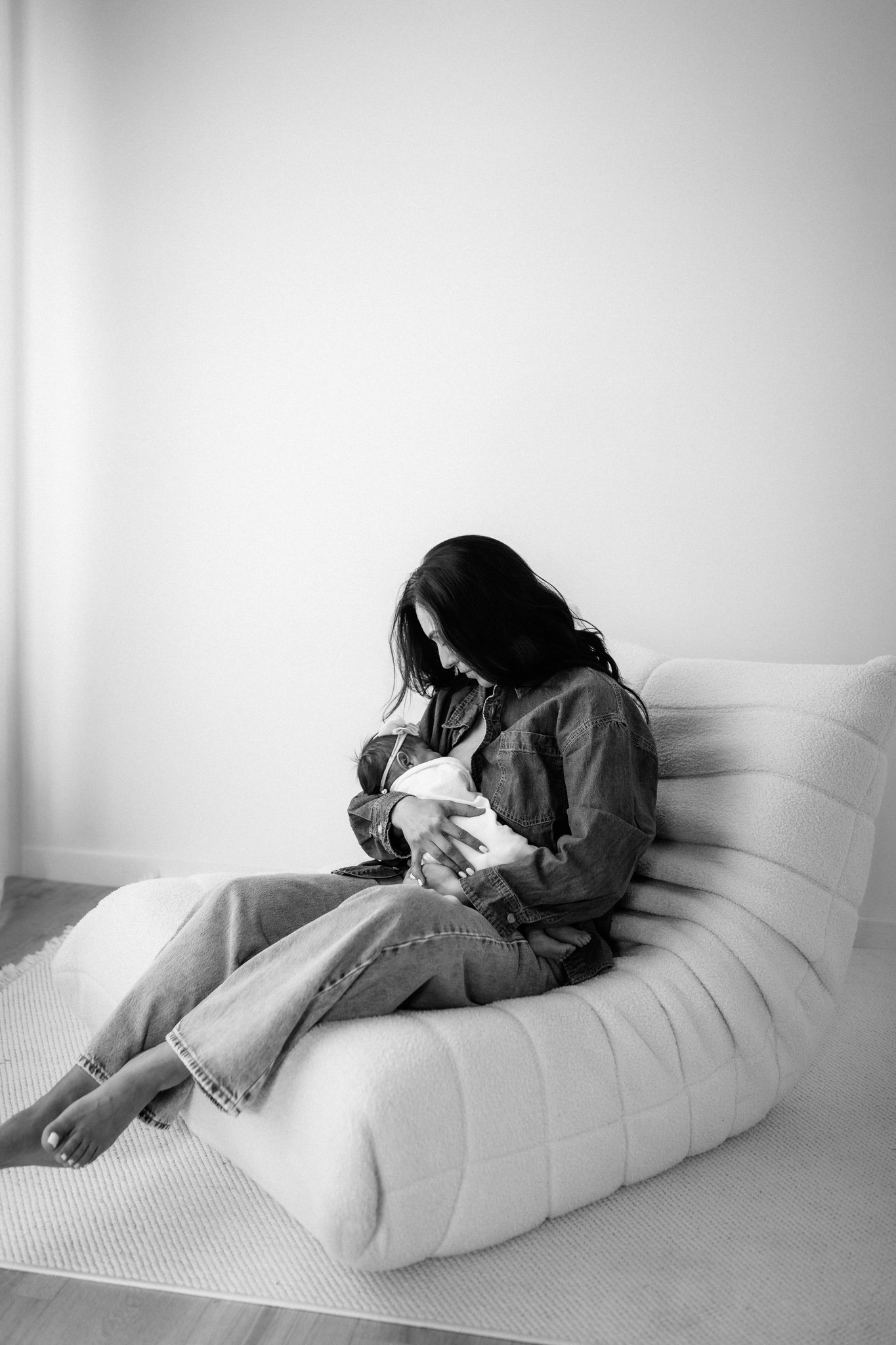Mother cradling her newborn baby in a black and white portrait.