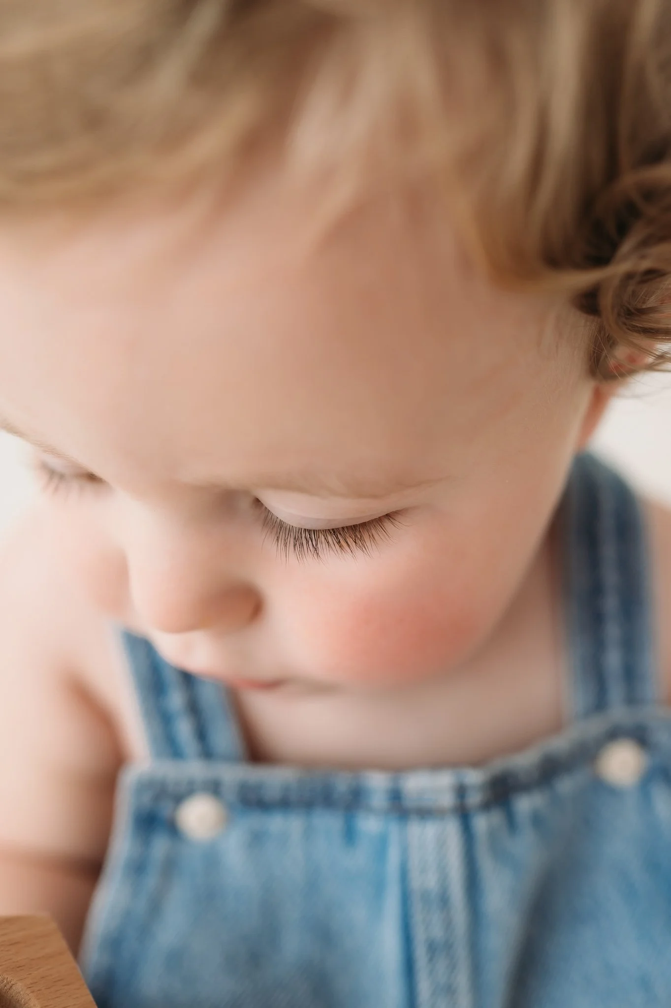 close up of toddler in denim overalls during milestone session The Woodlands TX