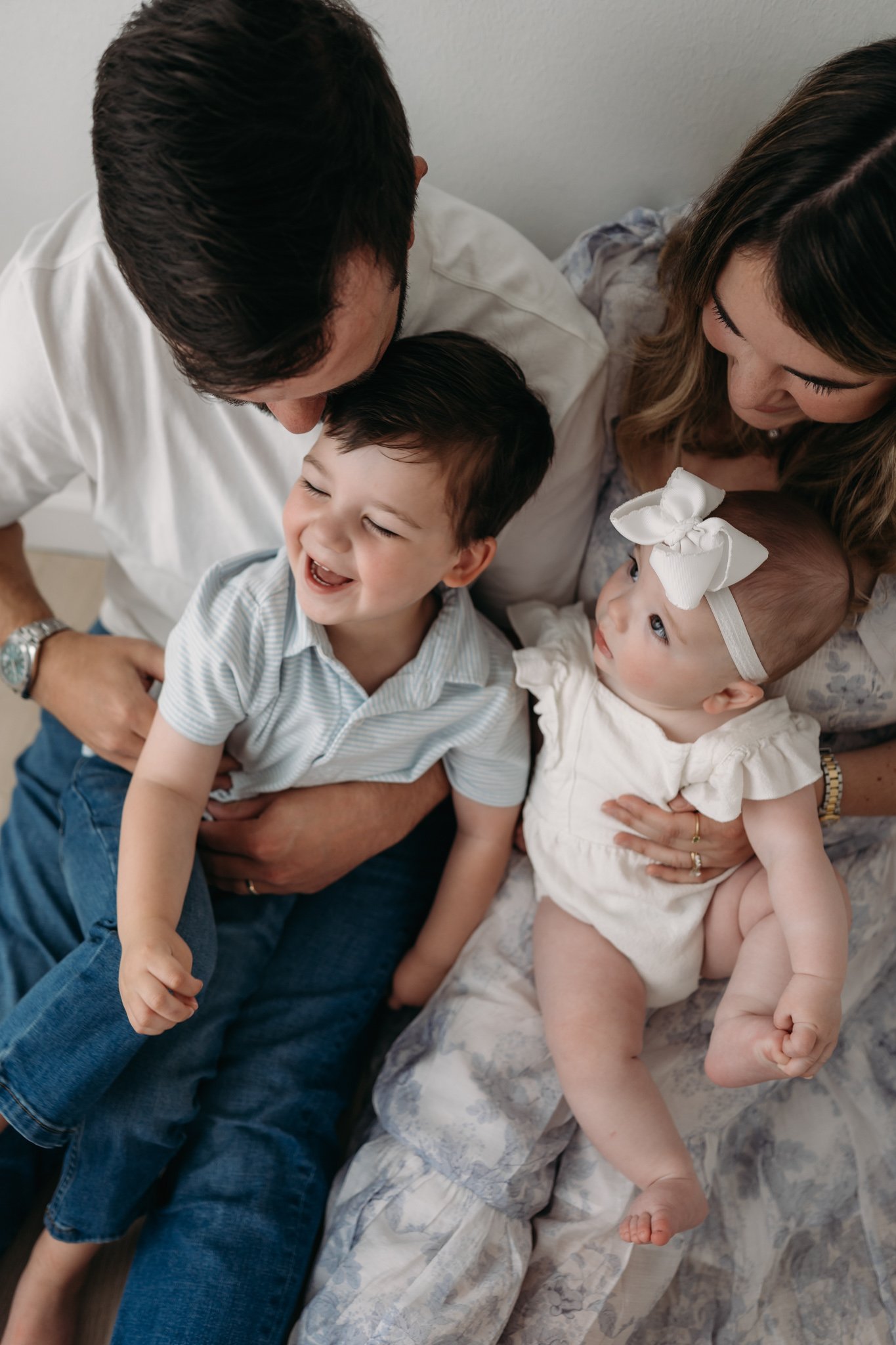 close up of parents smiling at laughing toddler and baby during family session The Woodlands TX