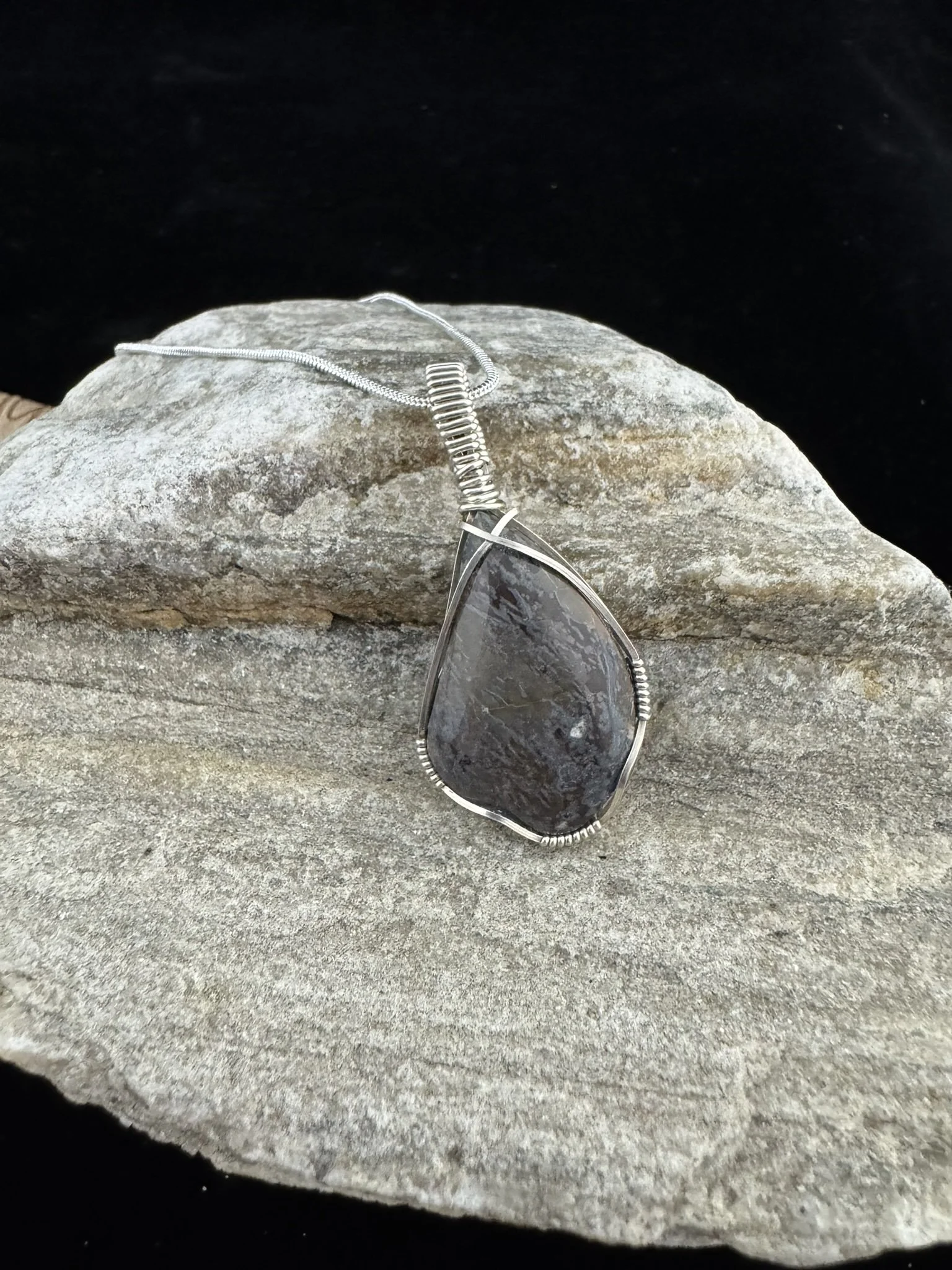 Dinosaur gem bone pendant wrapped in silver wire.